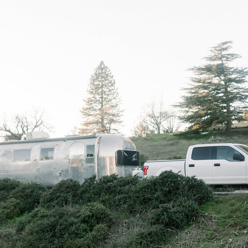 Airstream Travel Trailer RV being towed by a Truck on a road.