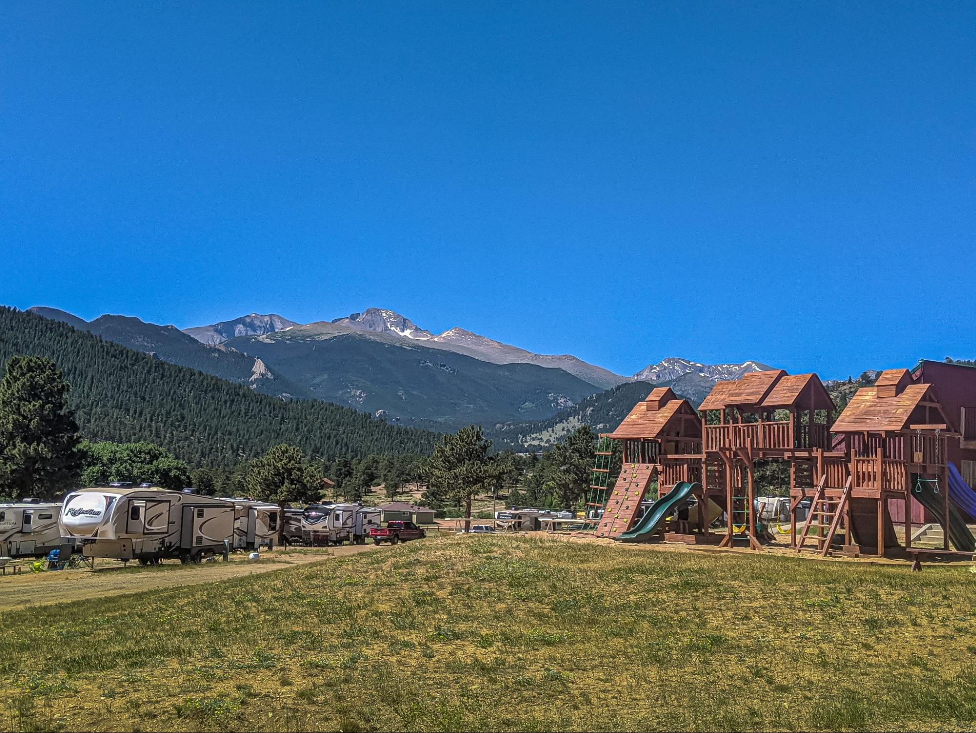 An RV park with a large playground in front of a mountain landscape. 