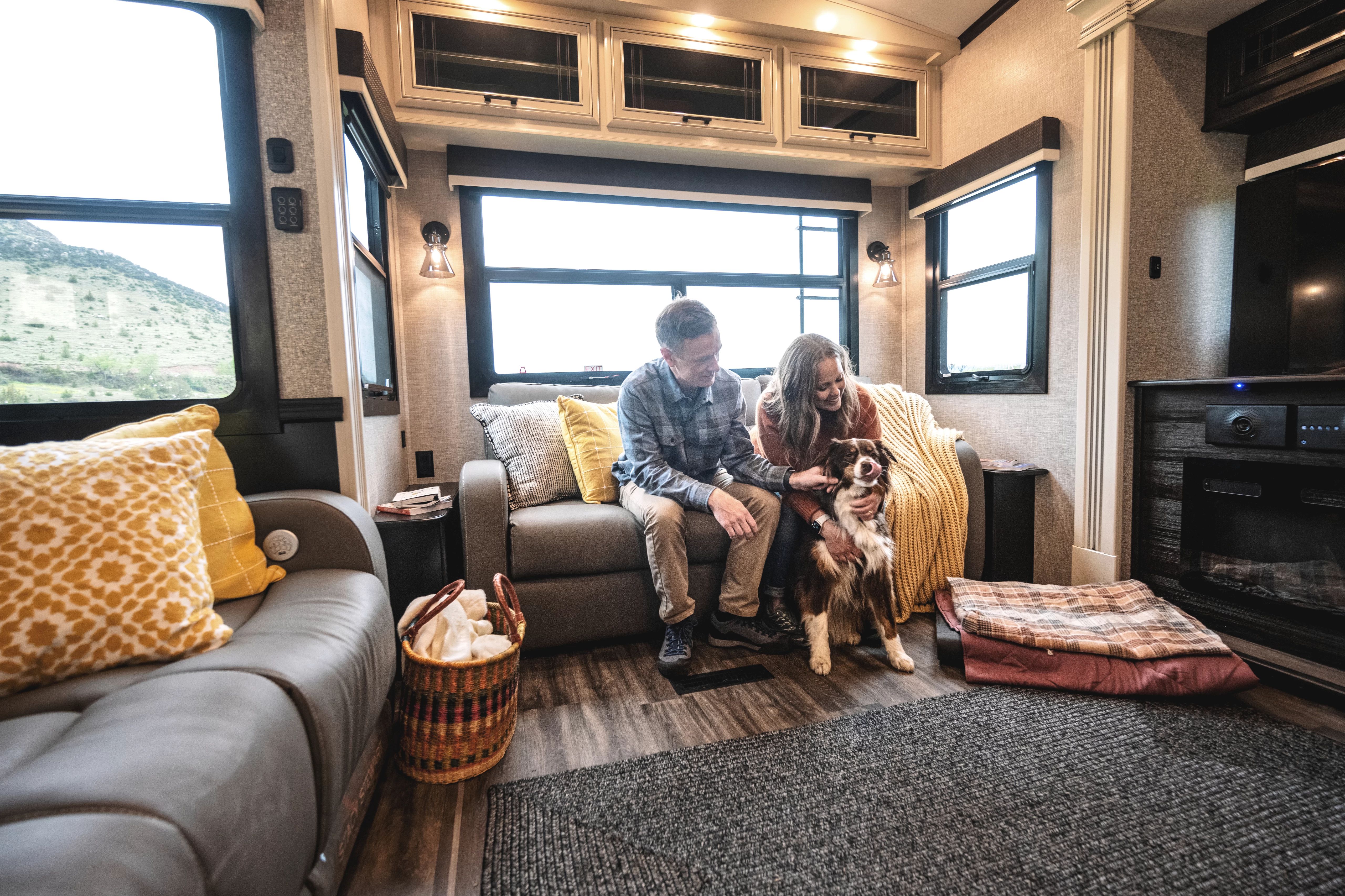 A couple sitting on a couch inside a Jayco Pinnacle Fifth Wheel RV