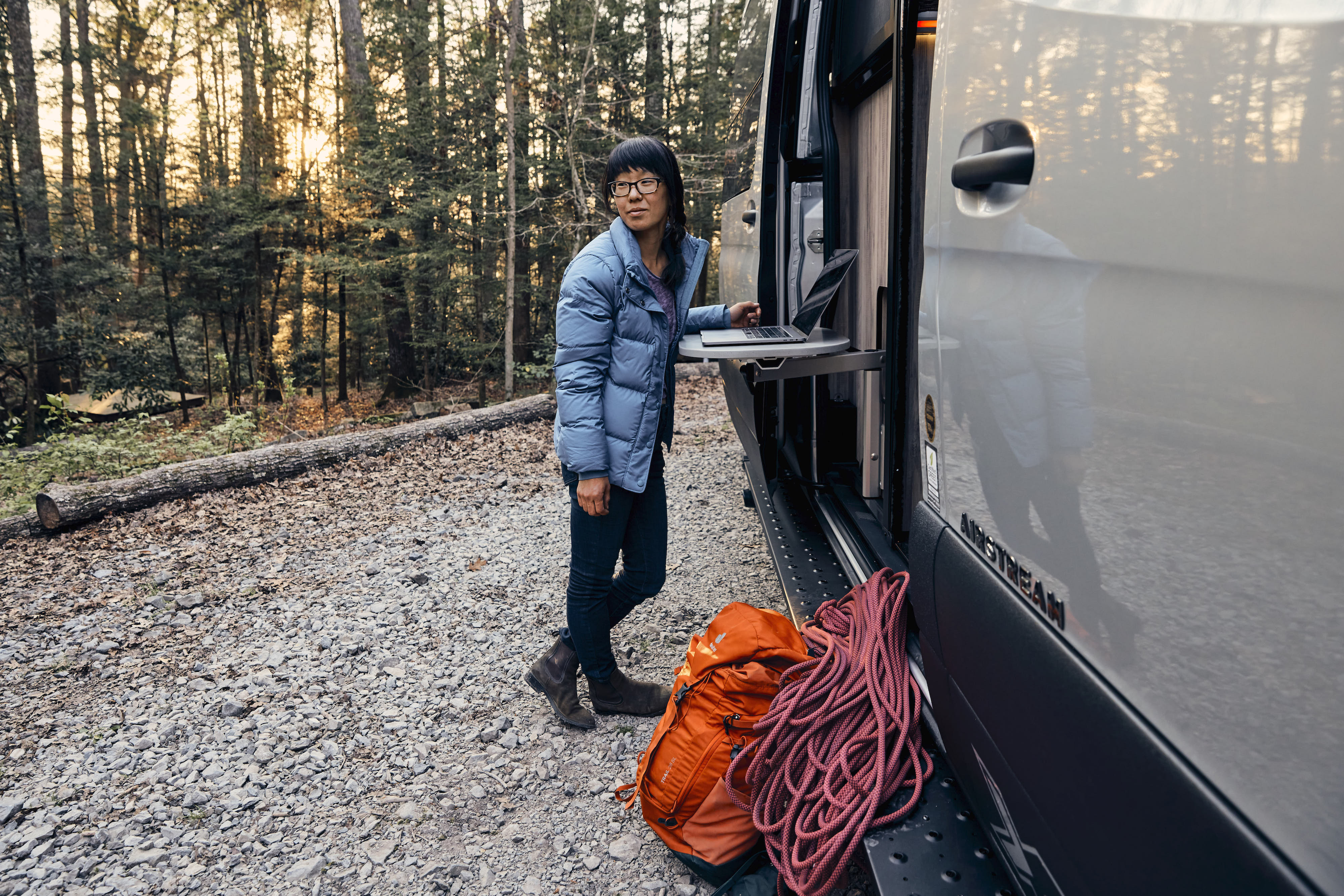 Kathy Karlo working on a laptop outside of an Airstream camper van