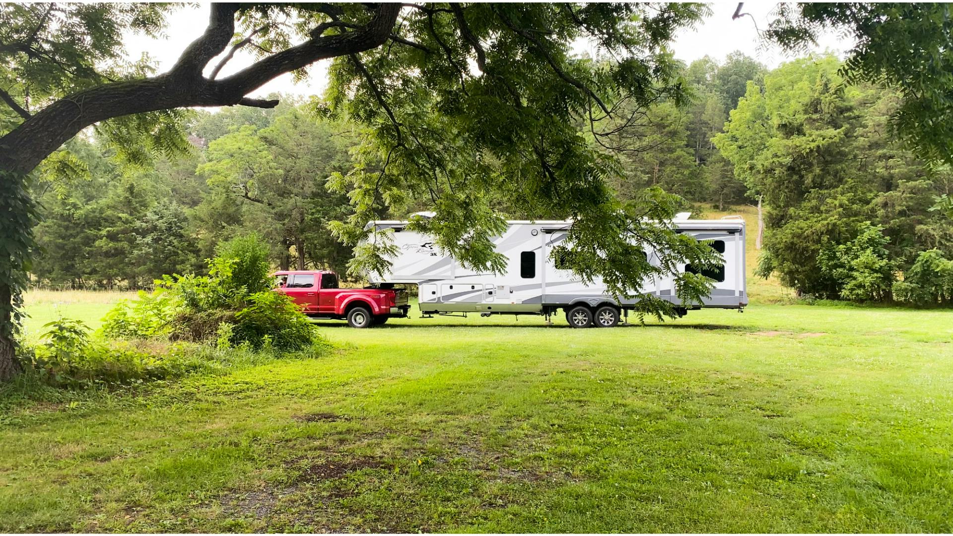 Red truck hitched to Open Range fifth wheel in grassy field