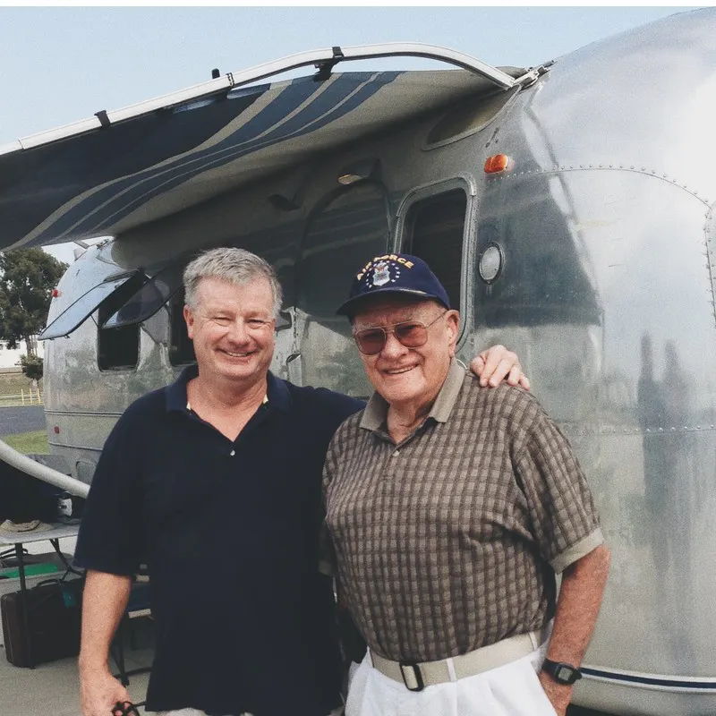 Billy and Grandpa Al standing in front of Airstream travel trailer. 