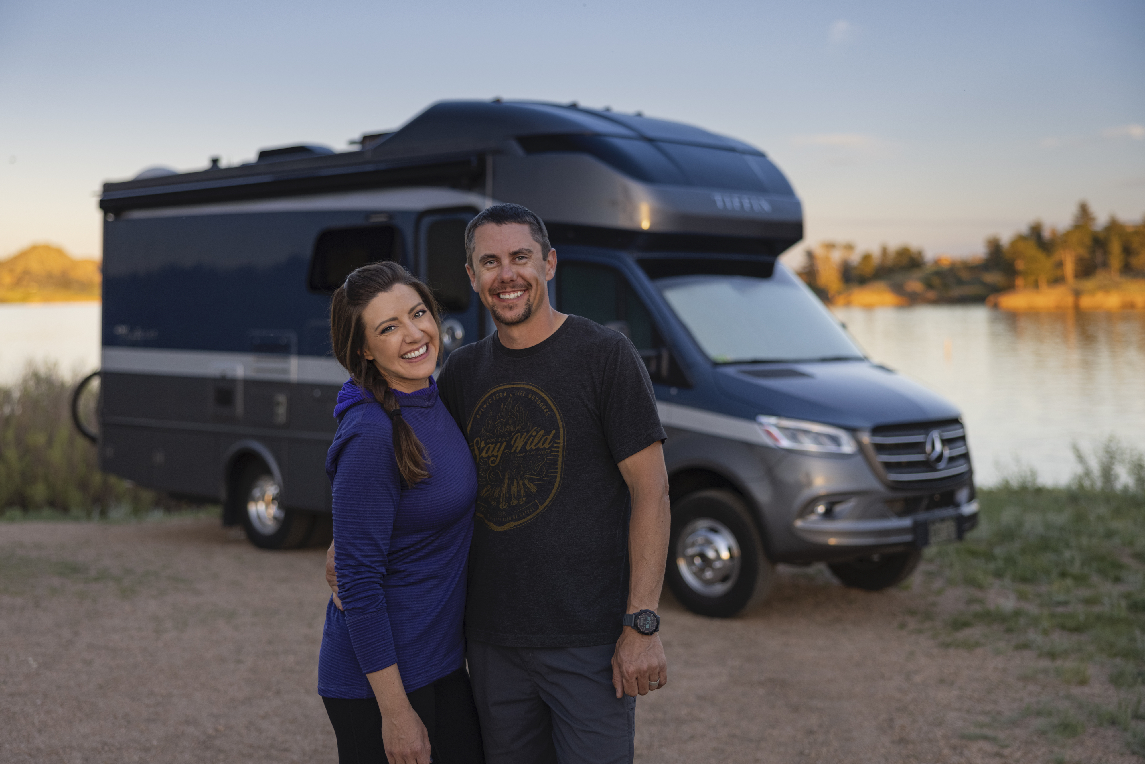 Dustin and Sarah smiling for a portrait in front of their Tiffin Wayfarer