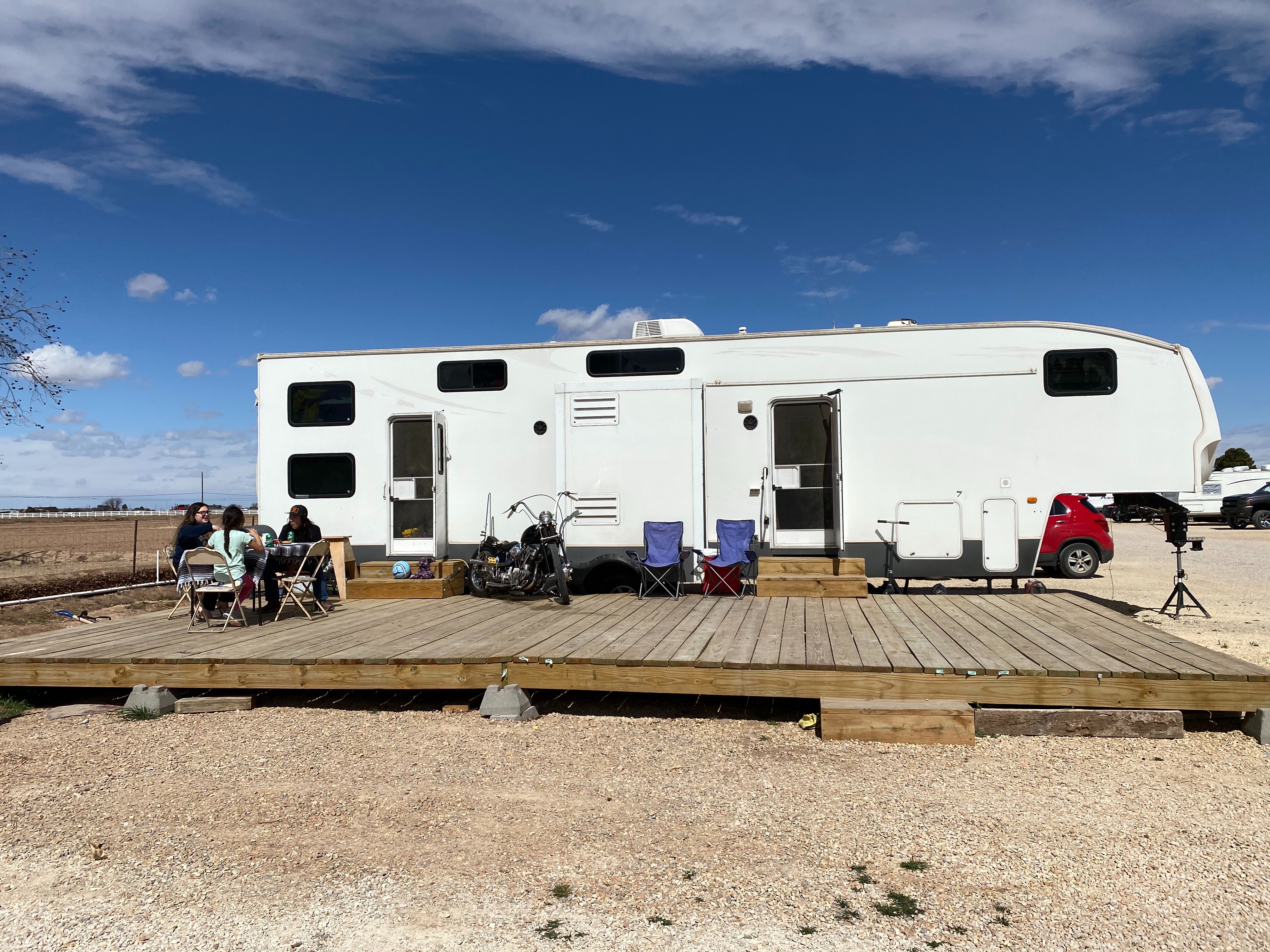 An RV parked at a desert campsite with an outdoor patio. 