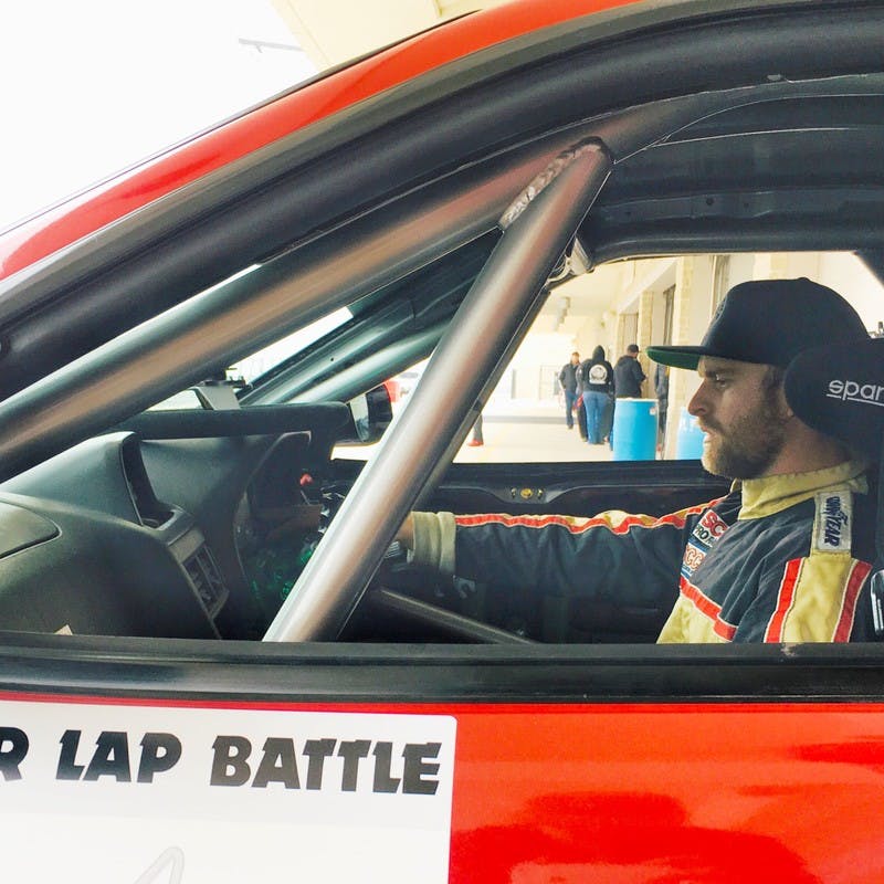 Man in a racecar outfit about to drive his racecar on the track. 