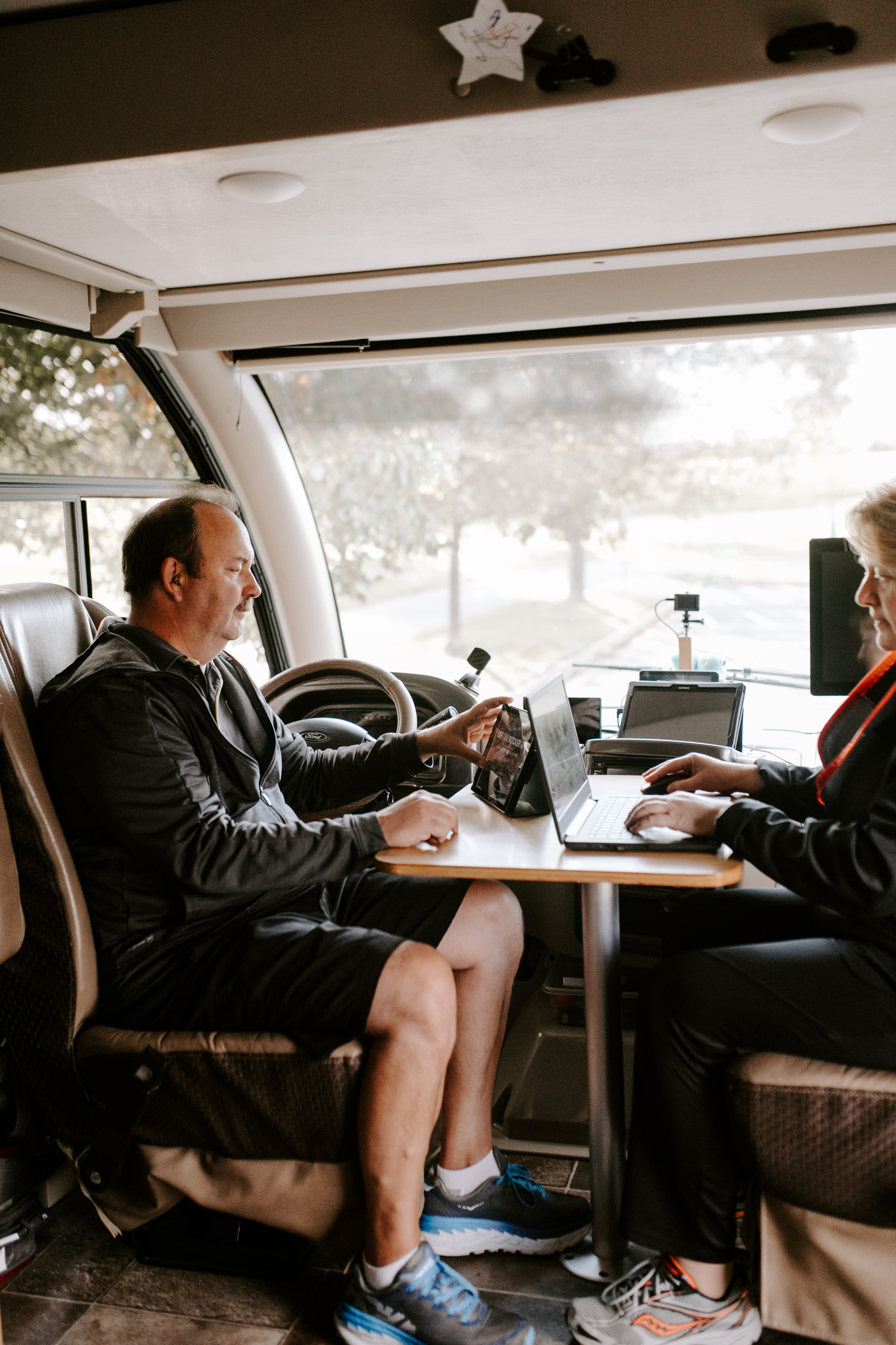 David and Kathy sitting at an RV desk with a laptop and a tablet.