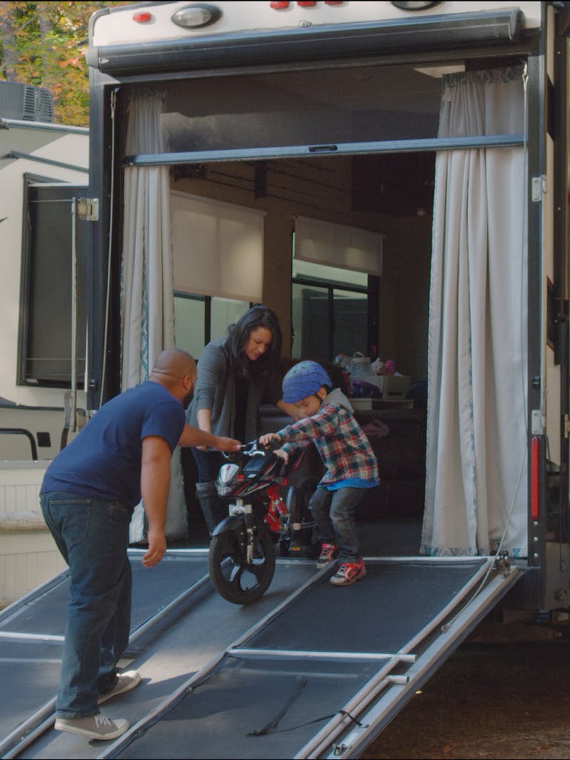 Luis and Sandra helping Julian wheel his bike out of the toy hauler RV.