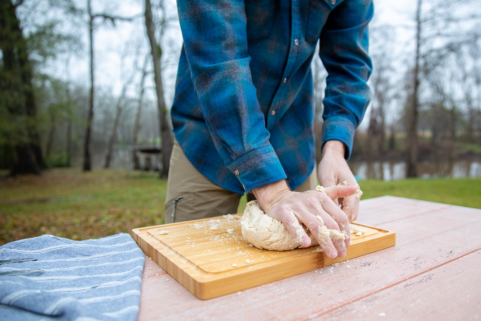 Kneading dough on a cutting board outside. 