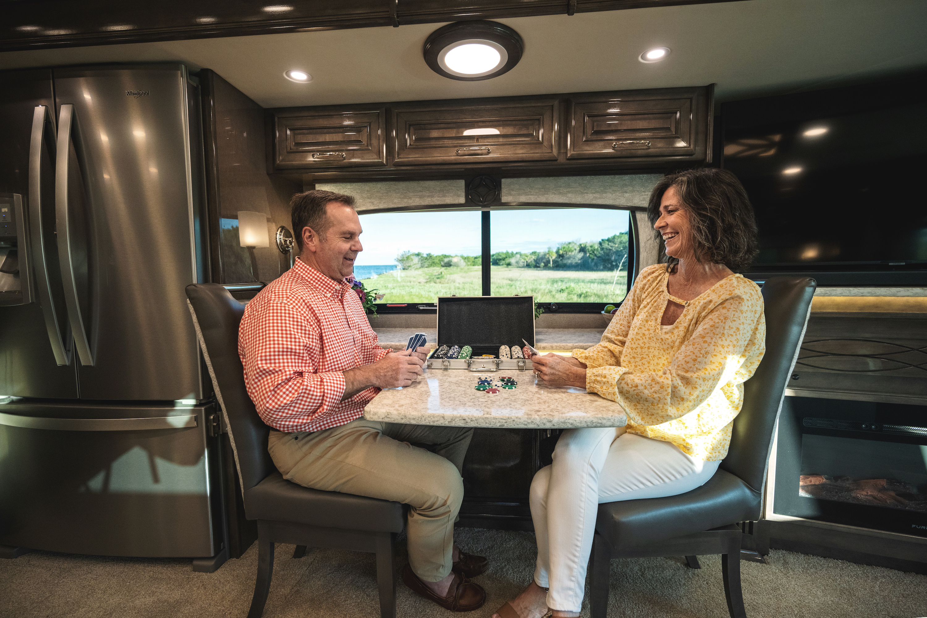 A couple plays cards in a Class C RV.