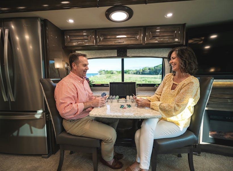 A couple plays cards in a Class C RV.