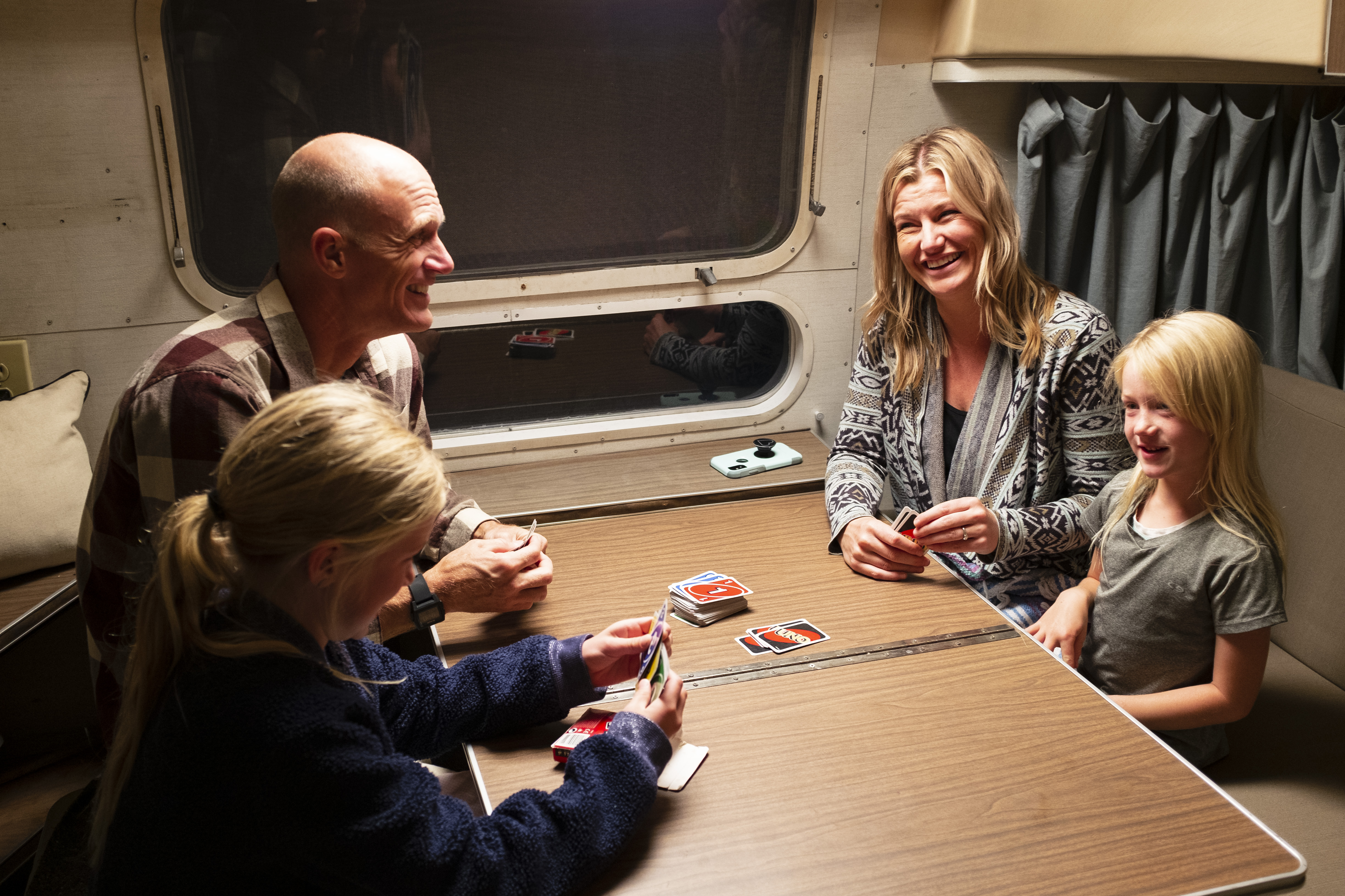 Two little girls and their mom and dad sitting at an RV table playing Uno.
