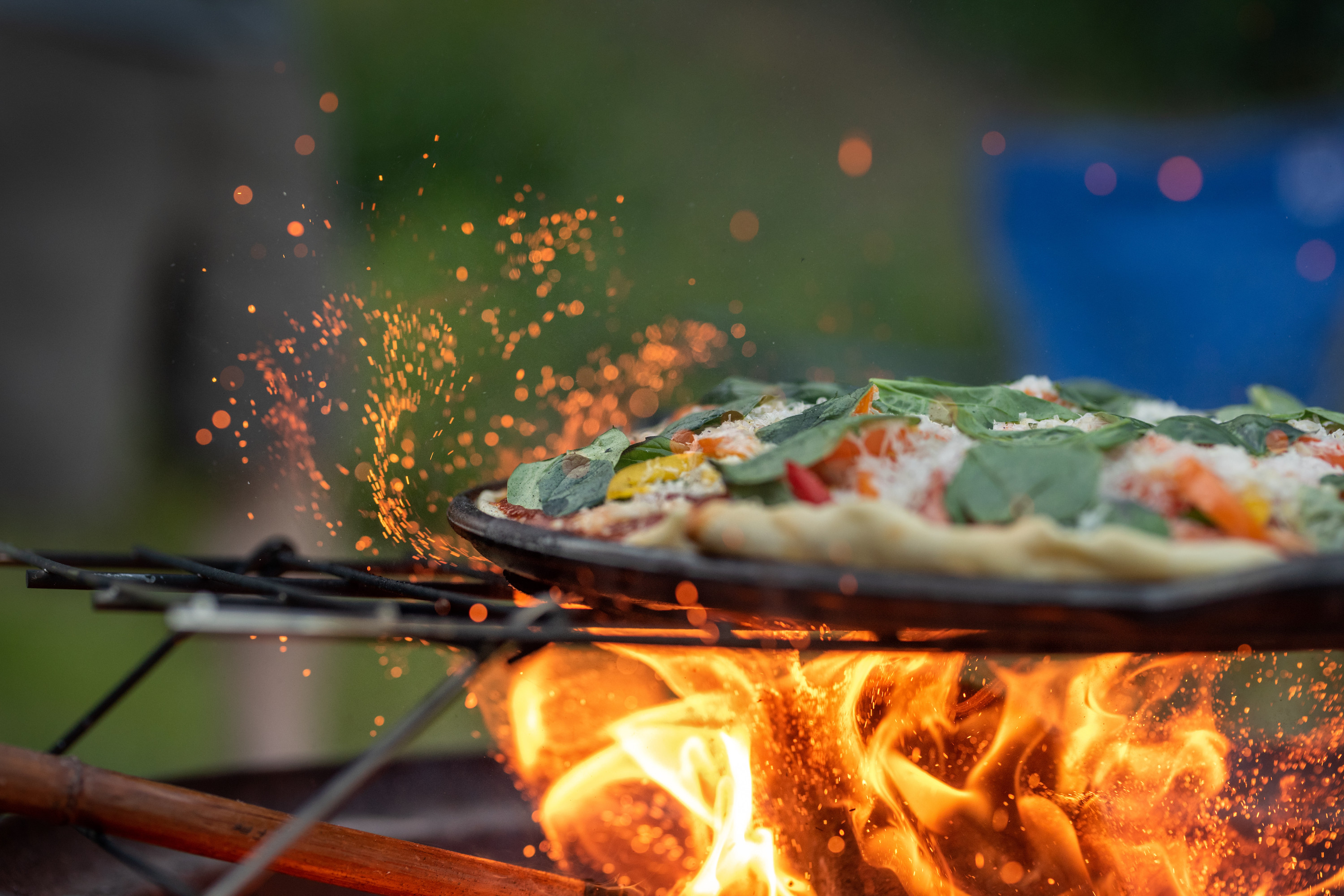 A pizza cooking over an open fire.