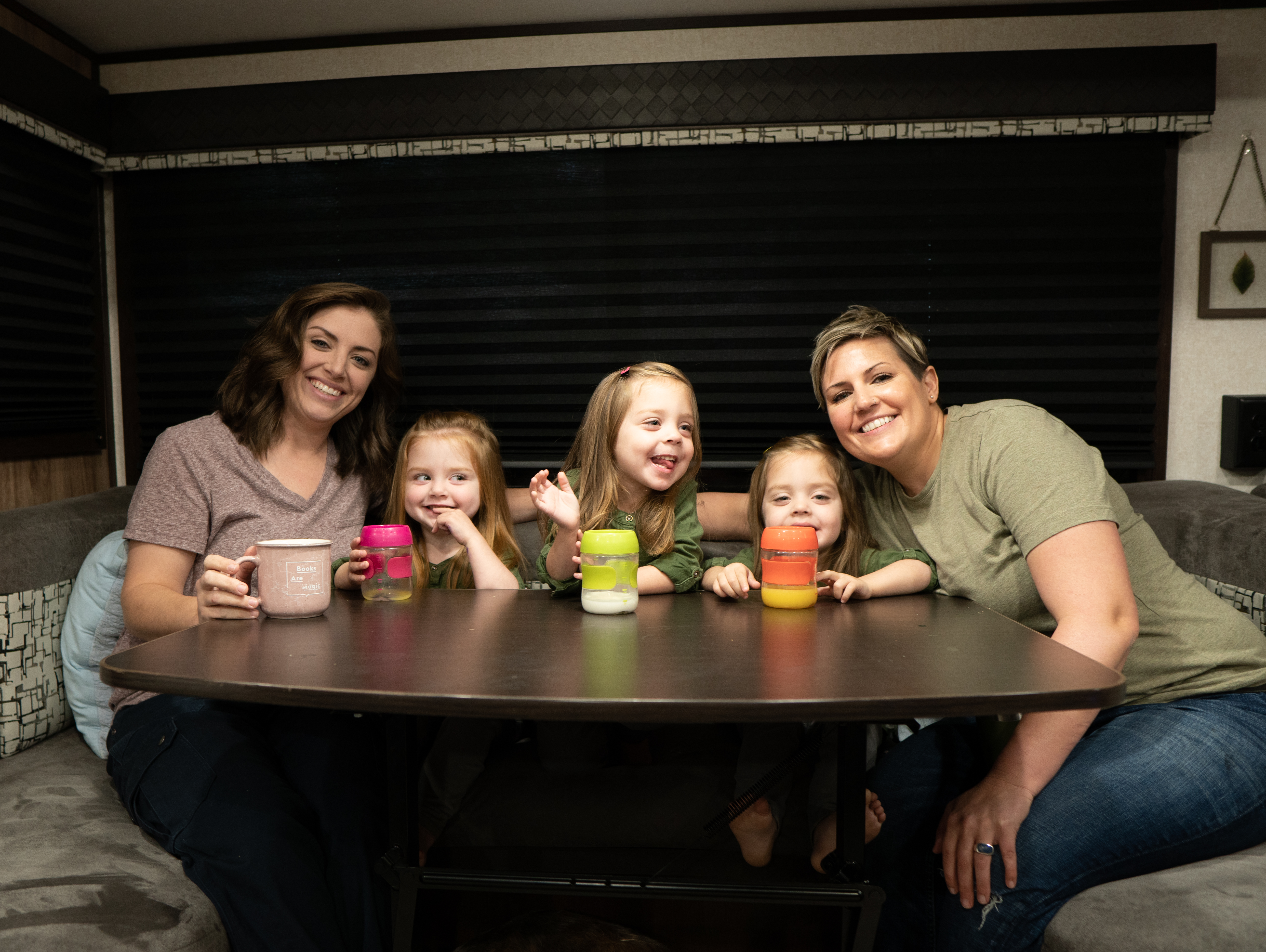 Two moms and triplet daughters around an RV  table drinking milk.
