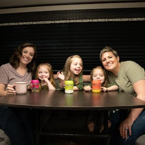 Two moms and triplet daughters around an RV  table drinking milk.