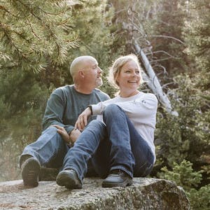Jason and Suzanne Talbot sitting on a rock in nature admiring the views around them.