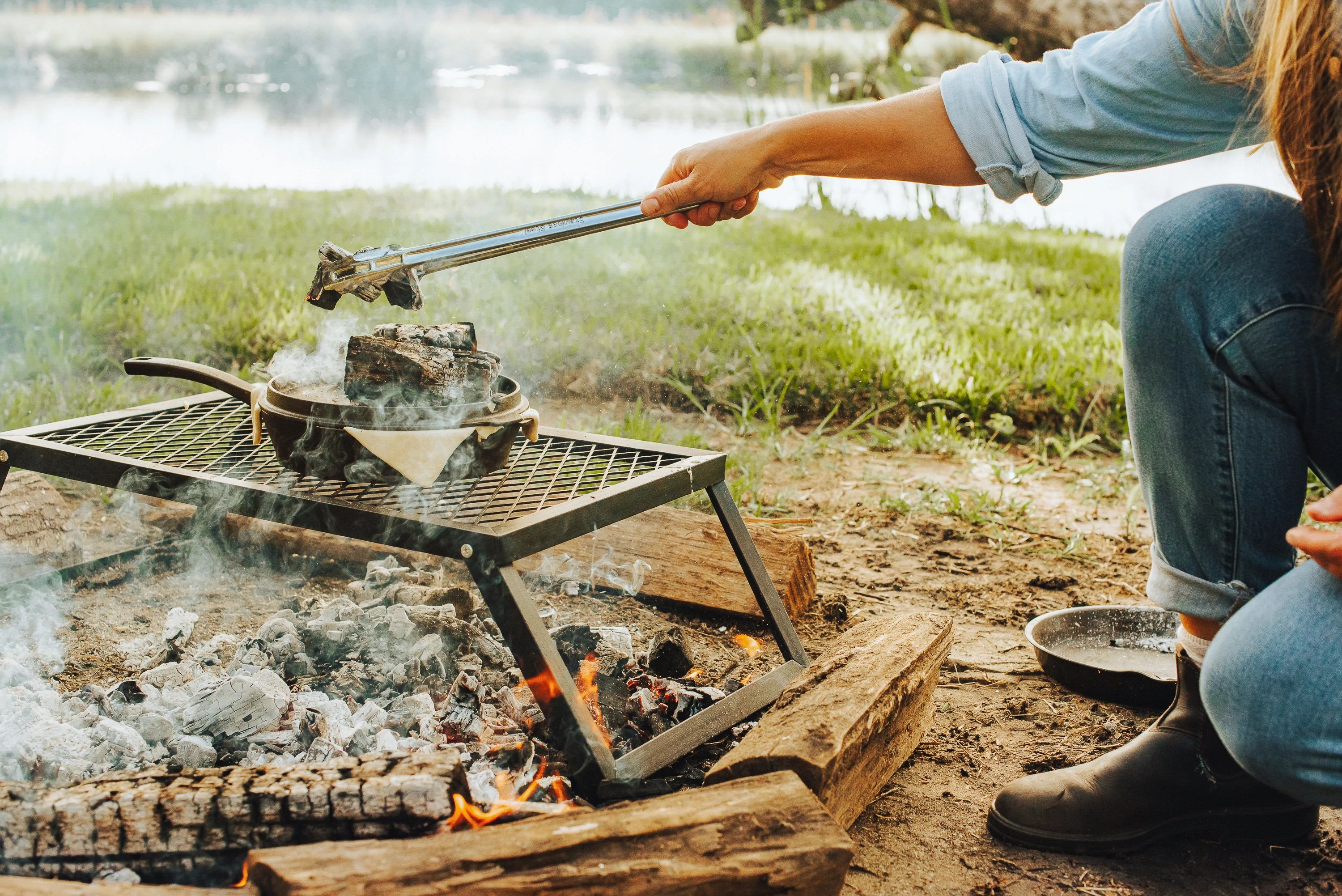 Sarah Glover putting hot coals over a dutch oven filled with lobster pie