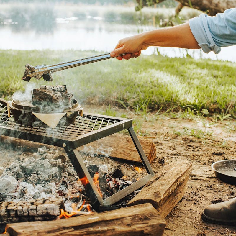 Sarah Glover putting hot coals over a dutch oven filled with lobster pie