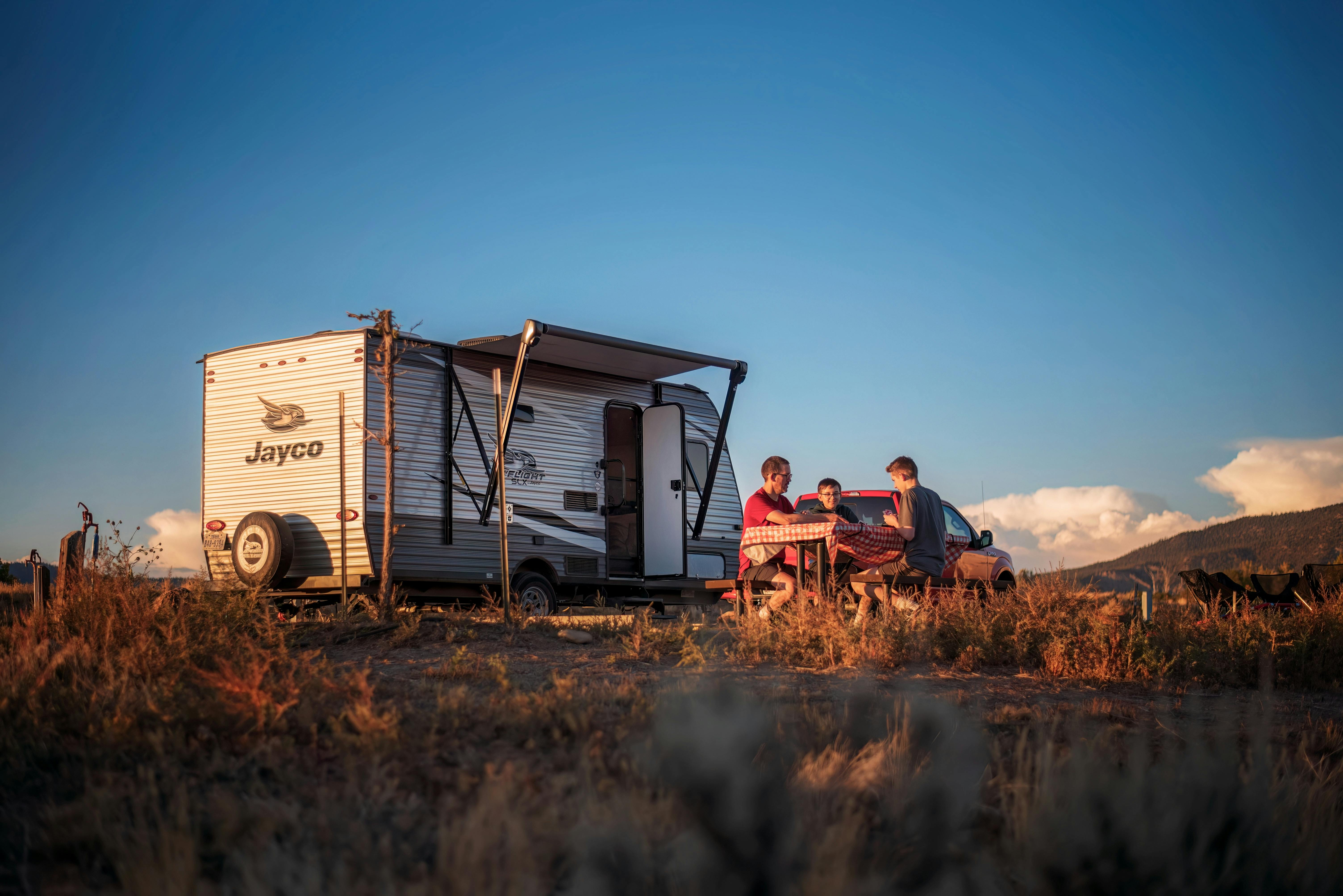 The Alison and Jason Takacs family sitting at a picnic table outside their Jayco Jay Flight