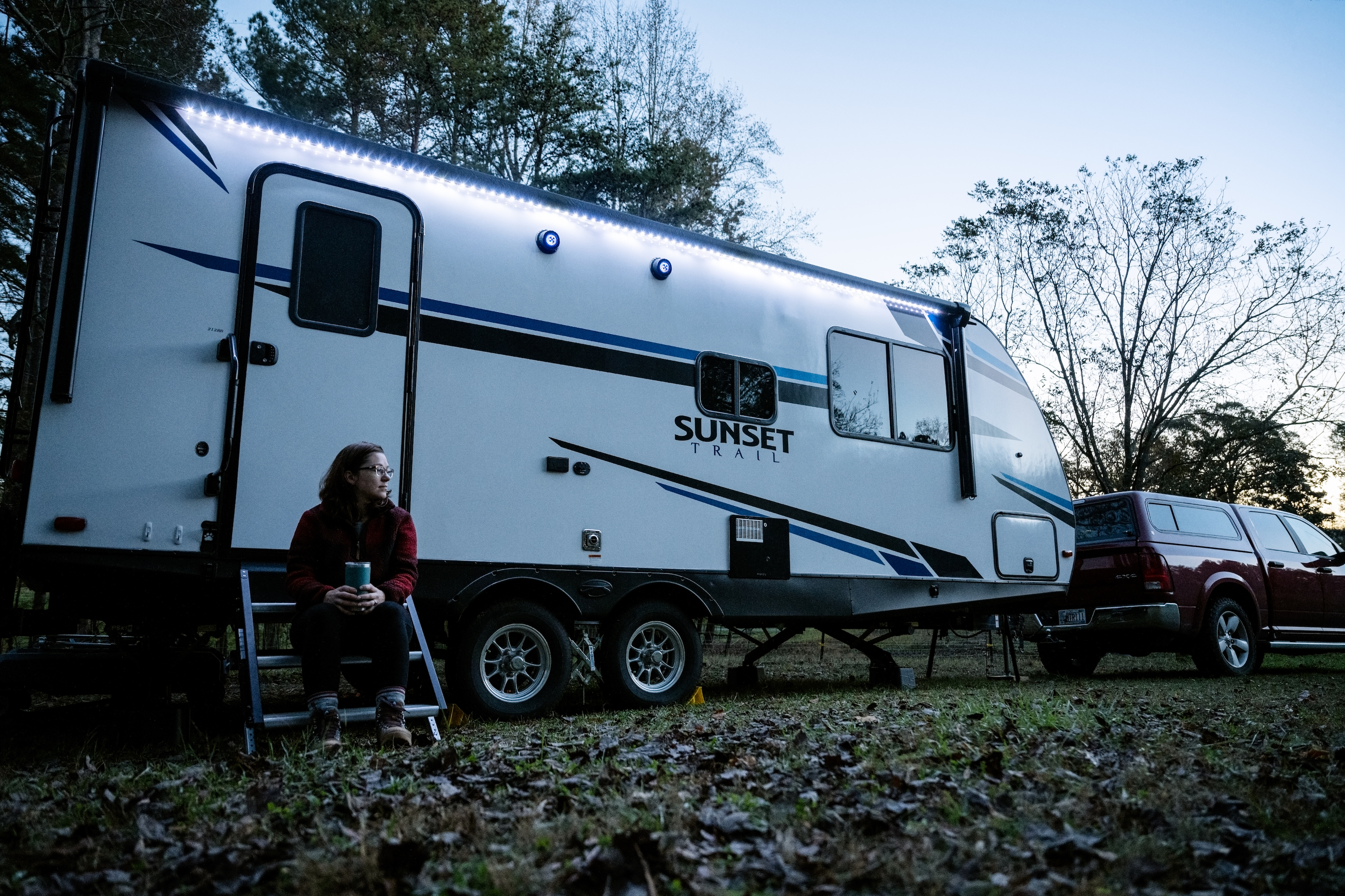 Marcia Schabel sitting on the steps of her Sunset Trail RV in the early morning with a cup of coffee.