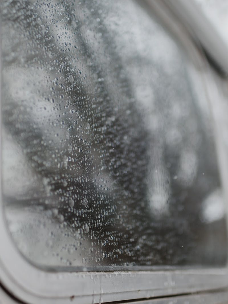 Gray shot, close up of rain and water on the window of an Airstream RV.