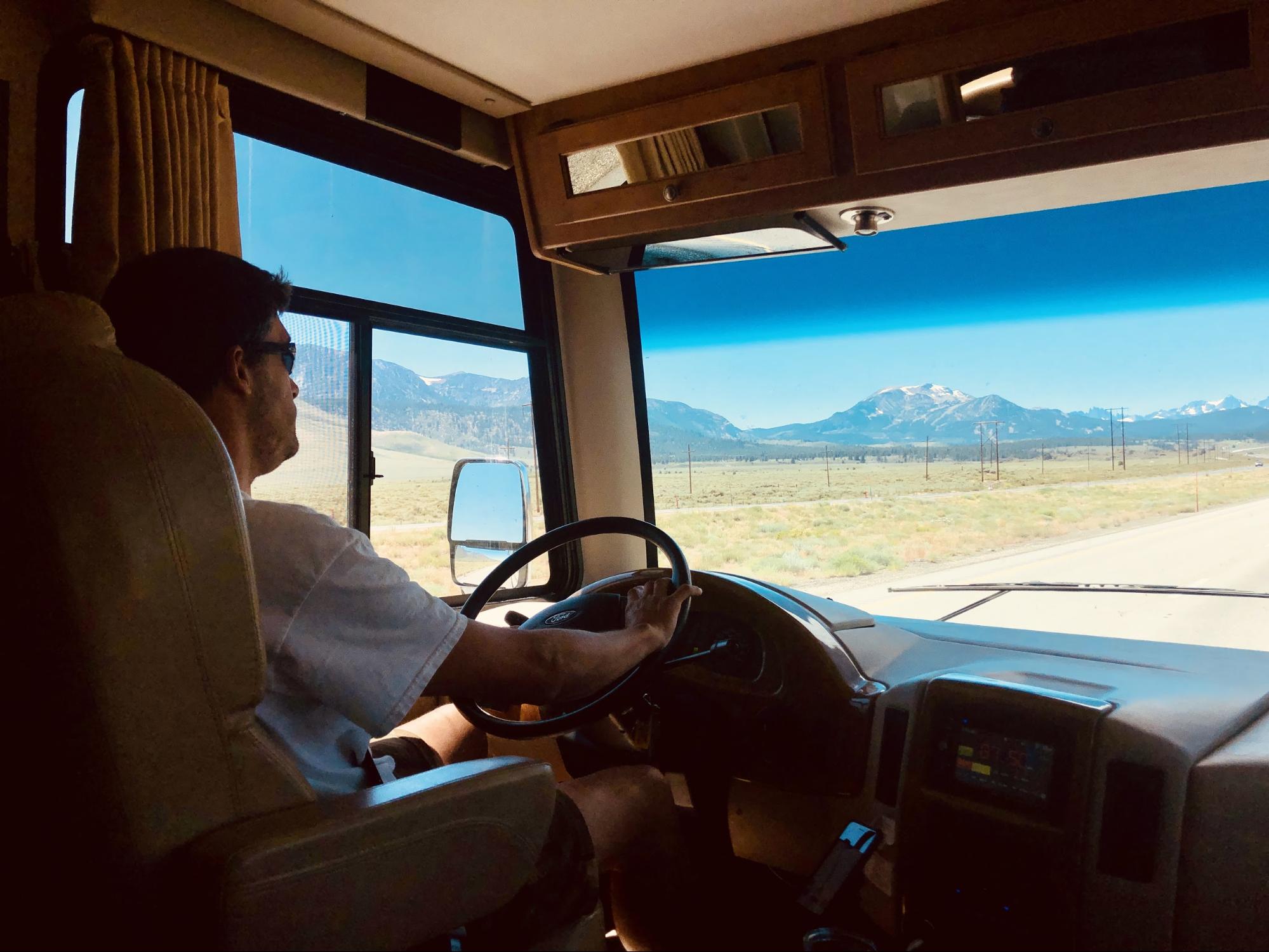Raoul Martinez driving and RV with snow capped mountains in view.