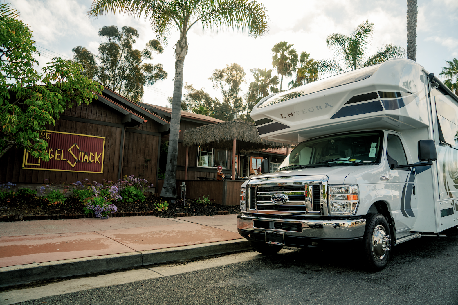 Class C Entegra Coach RV parked in front of small dark wood restaurant