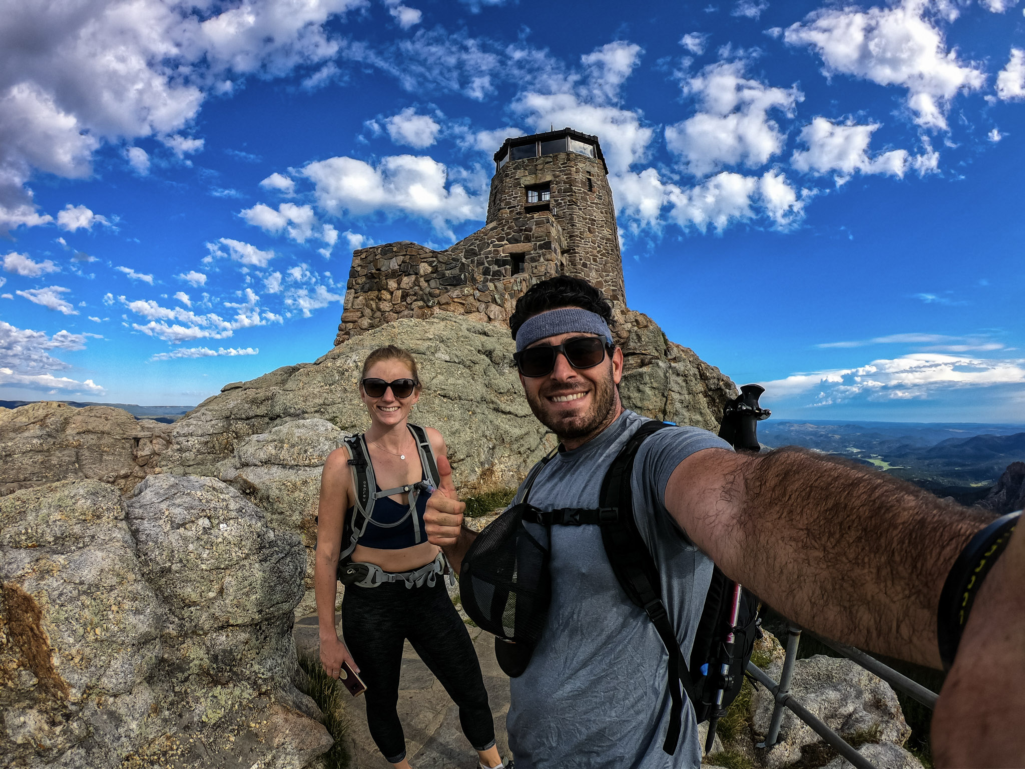 Jesse and Mel on top of a mountain with blue skies all around. 