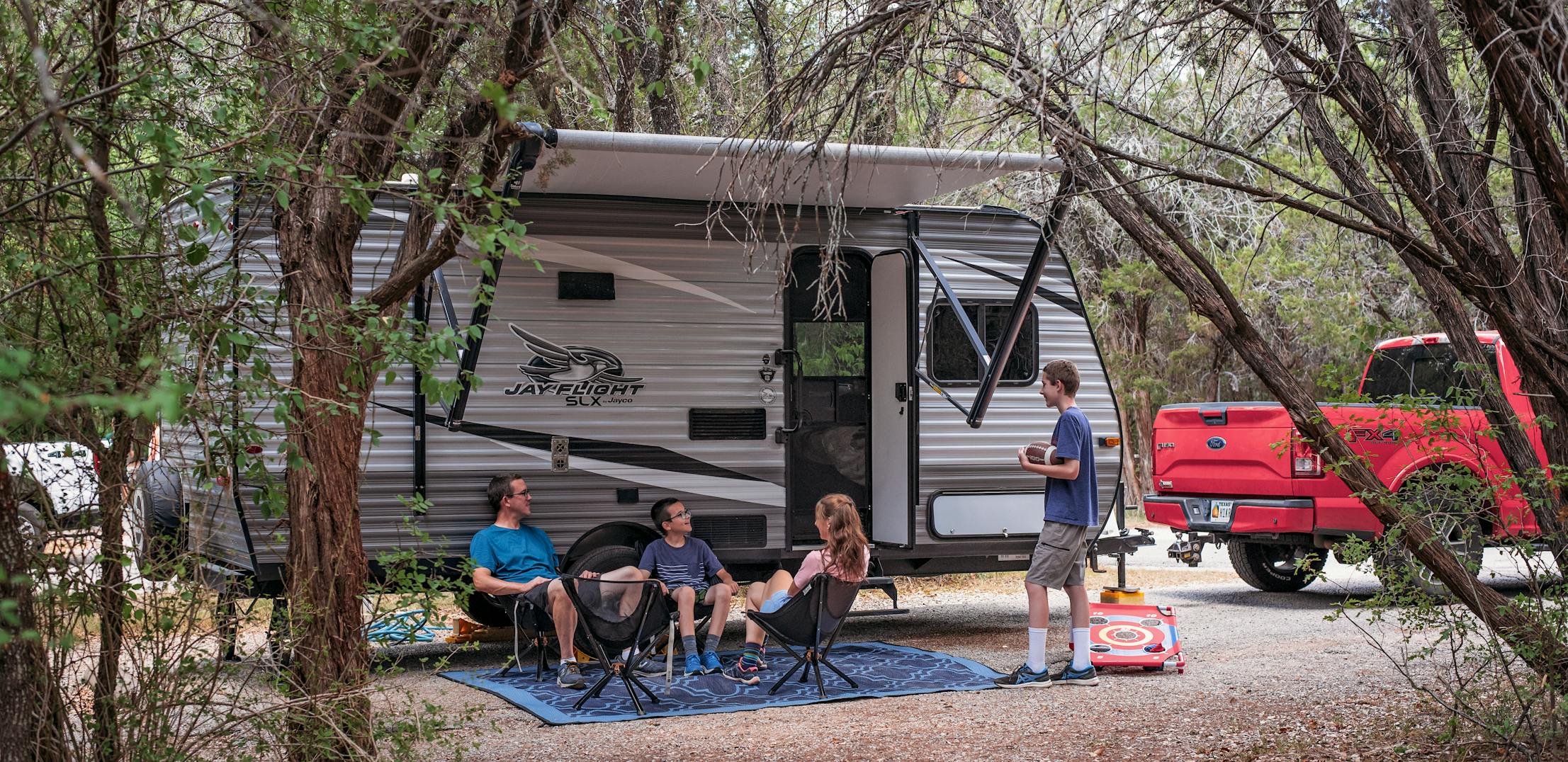 Alison Takacs and her family sitting in front of their RV at their campsite in Dinosaur Valley State Park