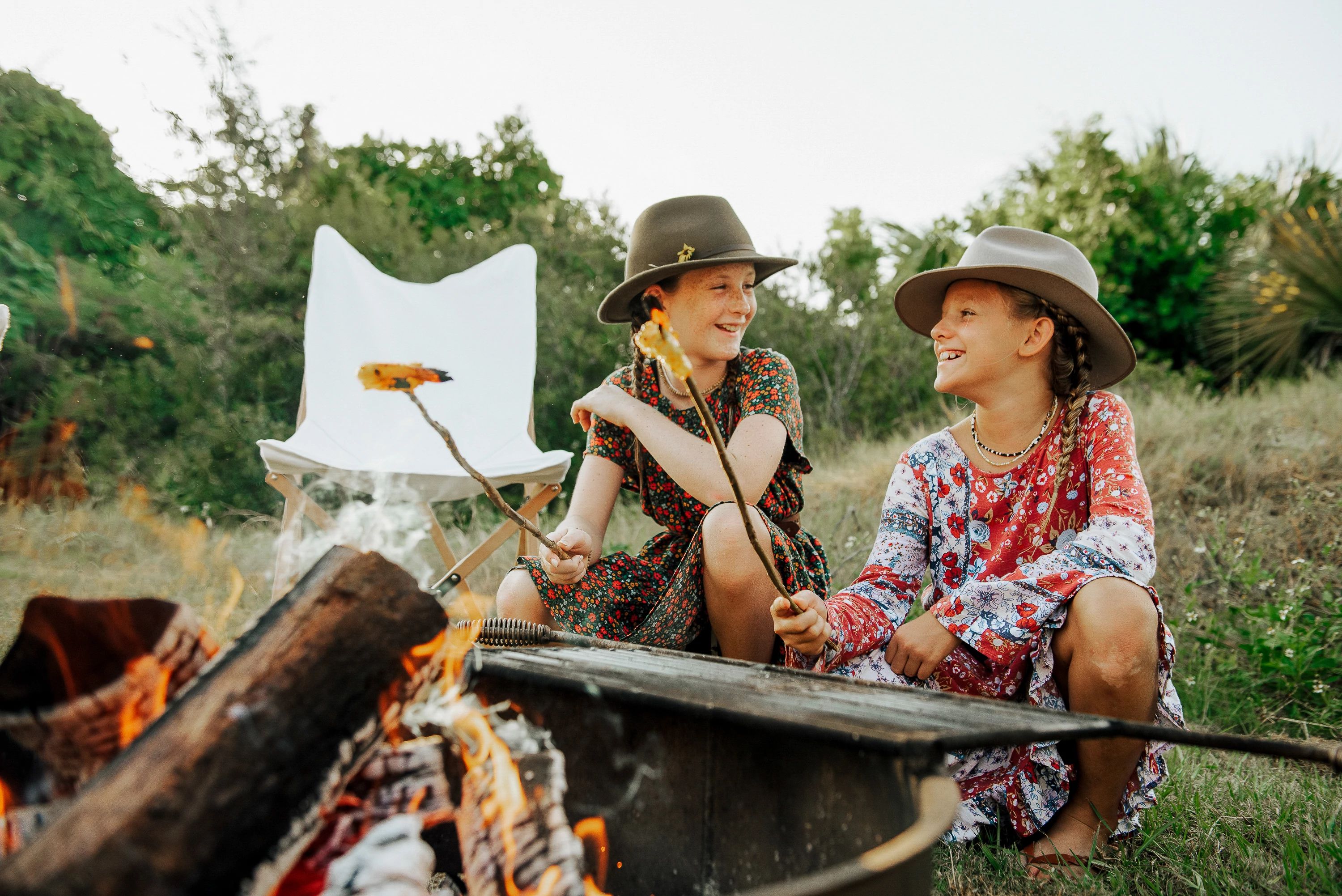 Girls smiling as they cook shrimp over a fire