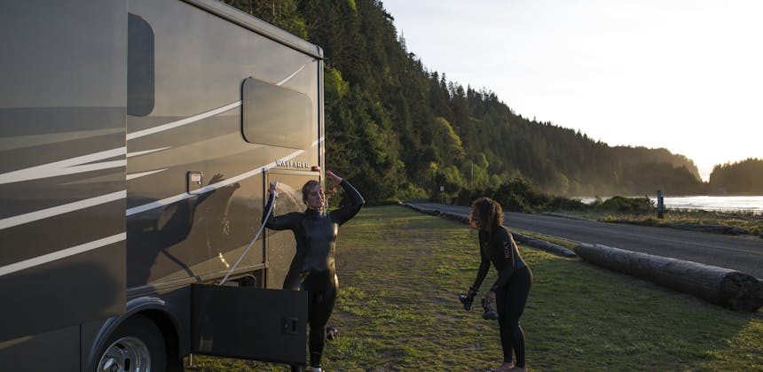 Chelsea and Layla rinsing off their body suits outside of a Tiffin Wayfarer RV