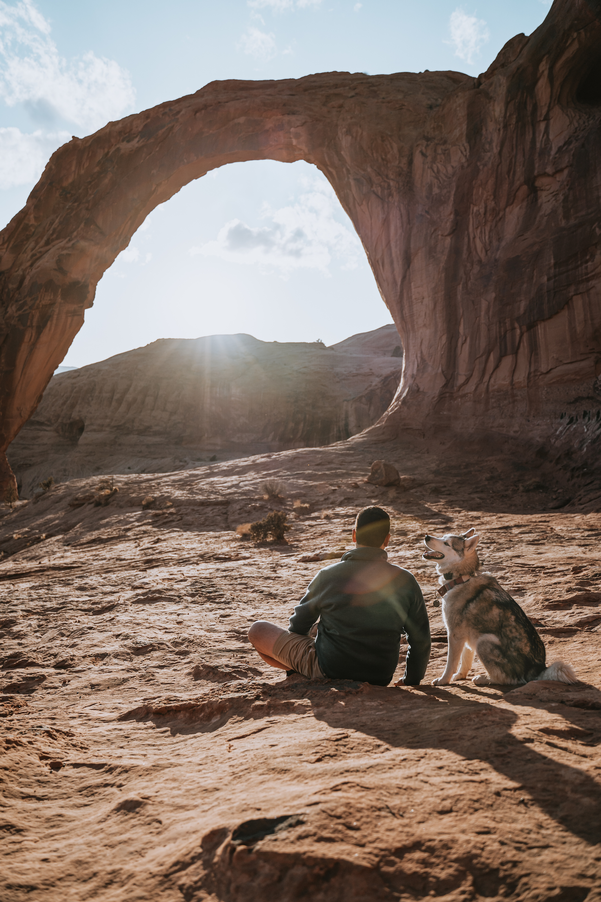 Nico and a husky watching the sun go down over a mountain crest. 