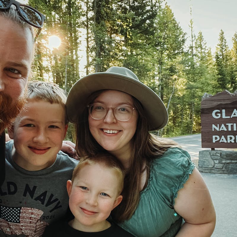 Andy and Kristen Murphy taking a family photo outside of Glacier National Park