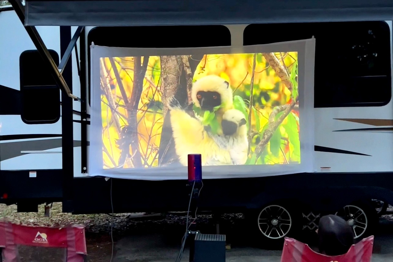 A movie plays on a projector screen outside of Bailey and Nicole Damberg's Dutchmen Astoria 