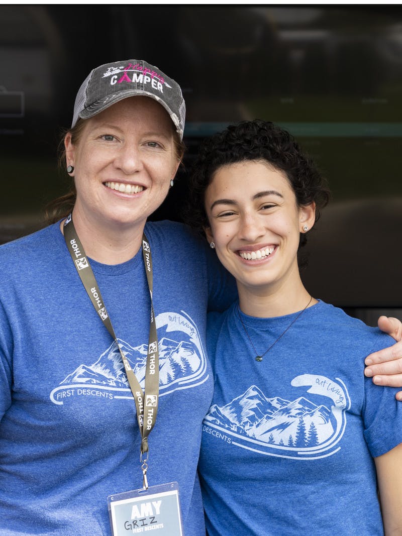Two participants from First Descents, as organization that creates unforgettable outdoor experiences for young adults effected by cancer, smile together.