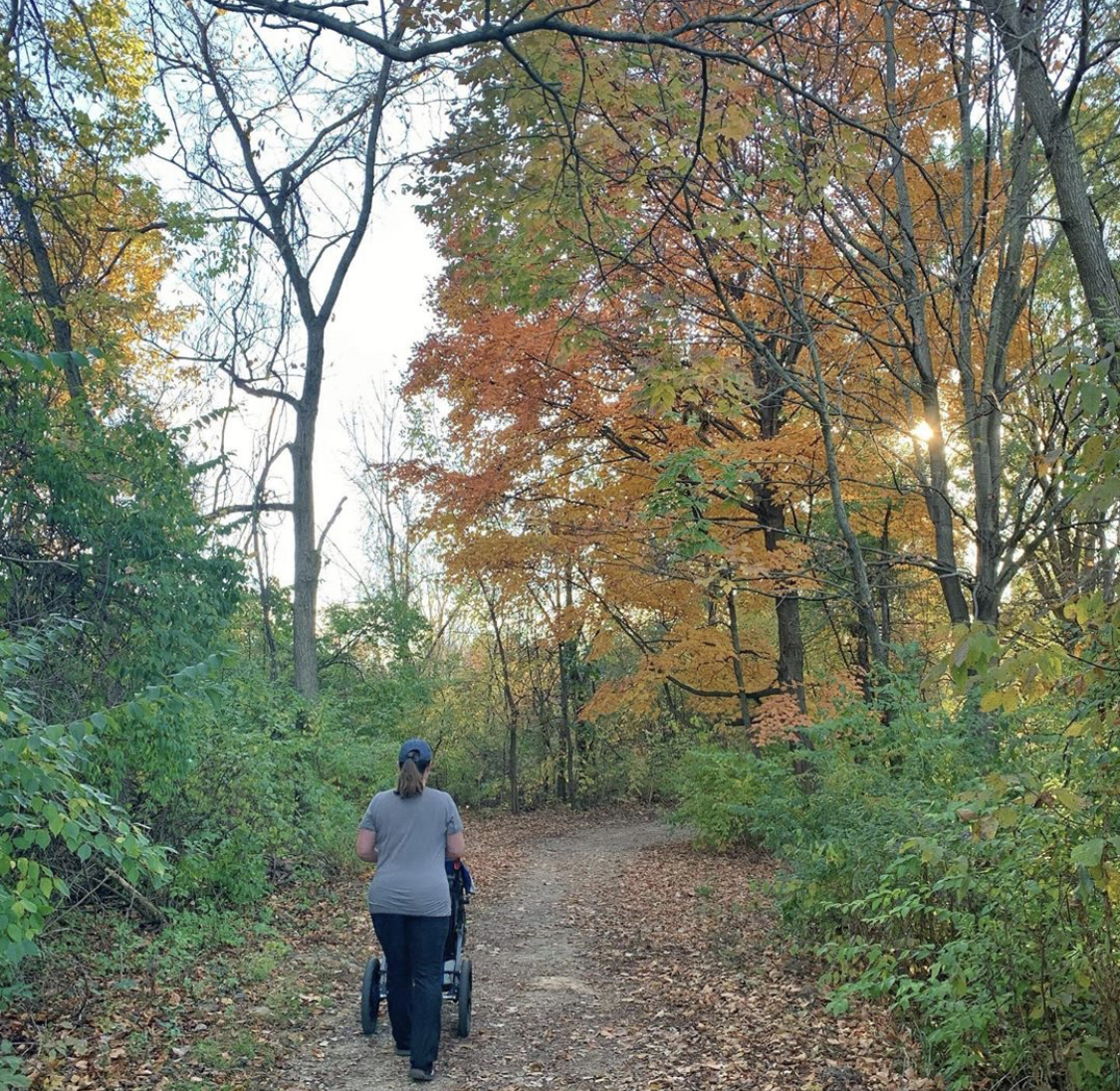 Brandy Gleason pushing a stroller on a tree-covered trail. 