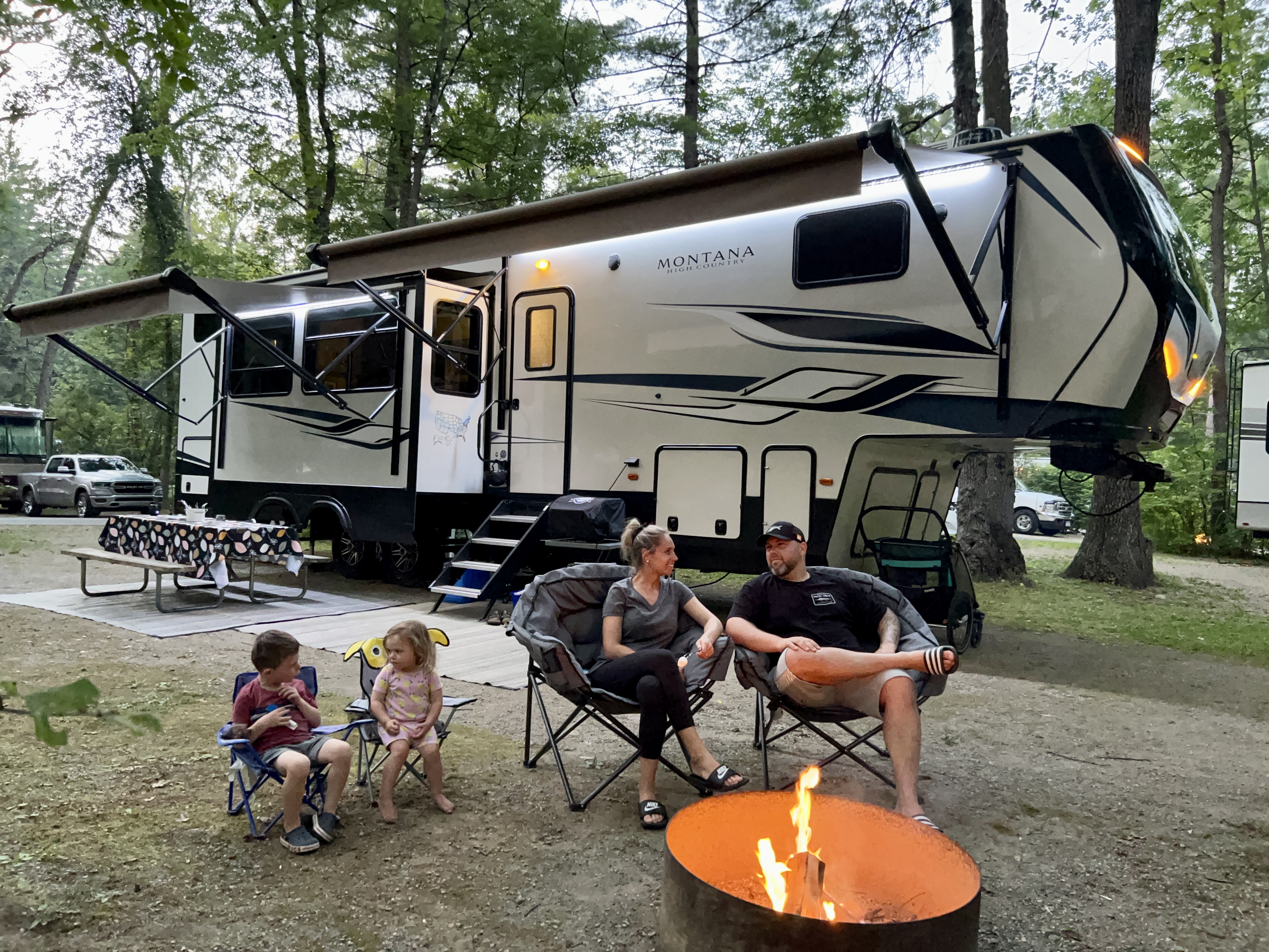 The Roy's sitting outside of their Keystone Montana around a campfire