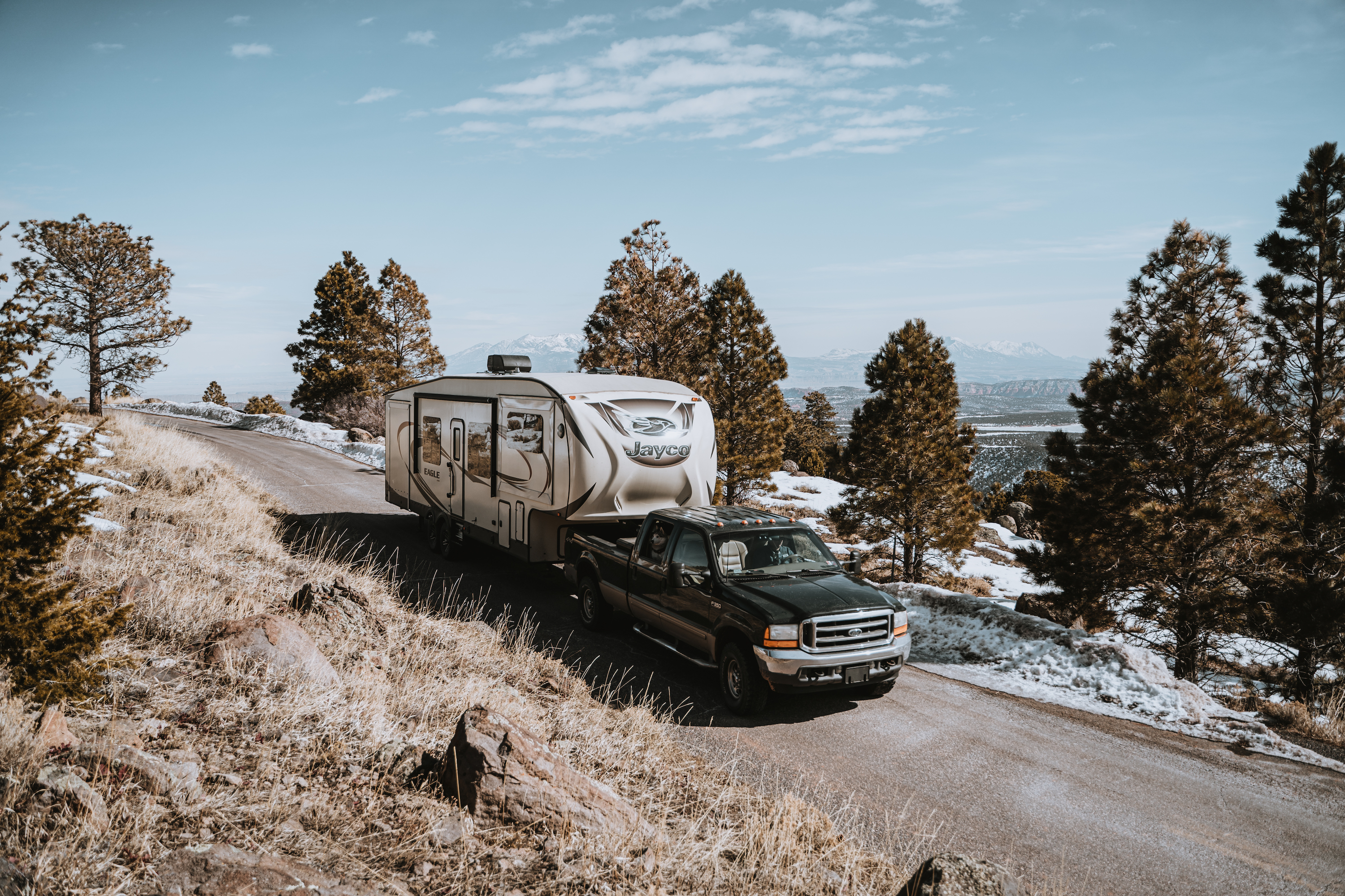 A truck towing a Jayco RV on a mountain road.