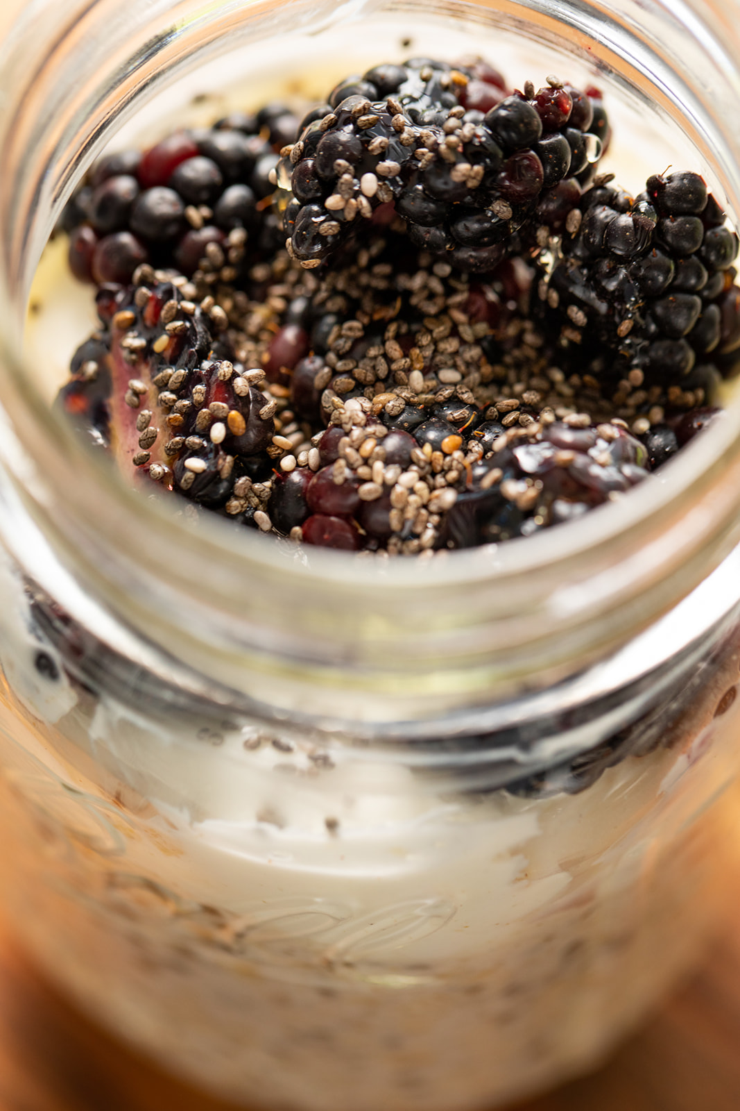 A close up shot of blackberries and chia seeds on top of overnight oats. 