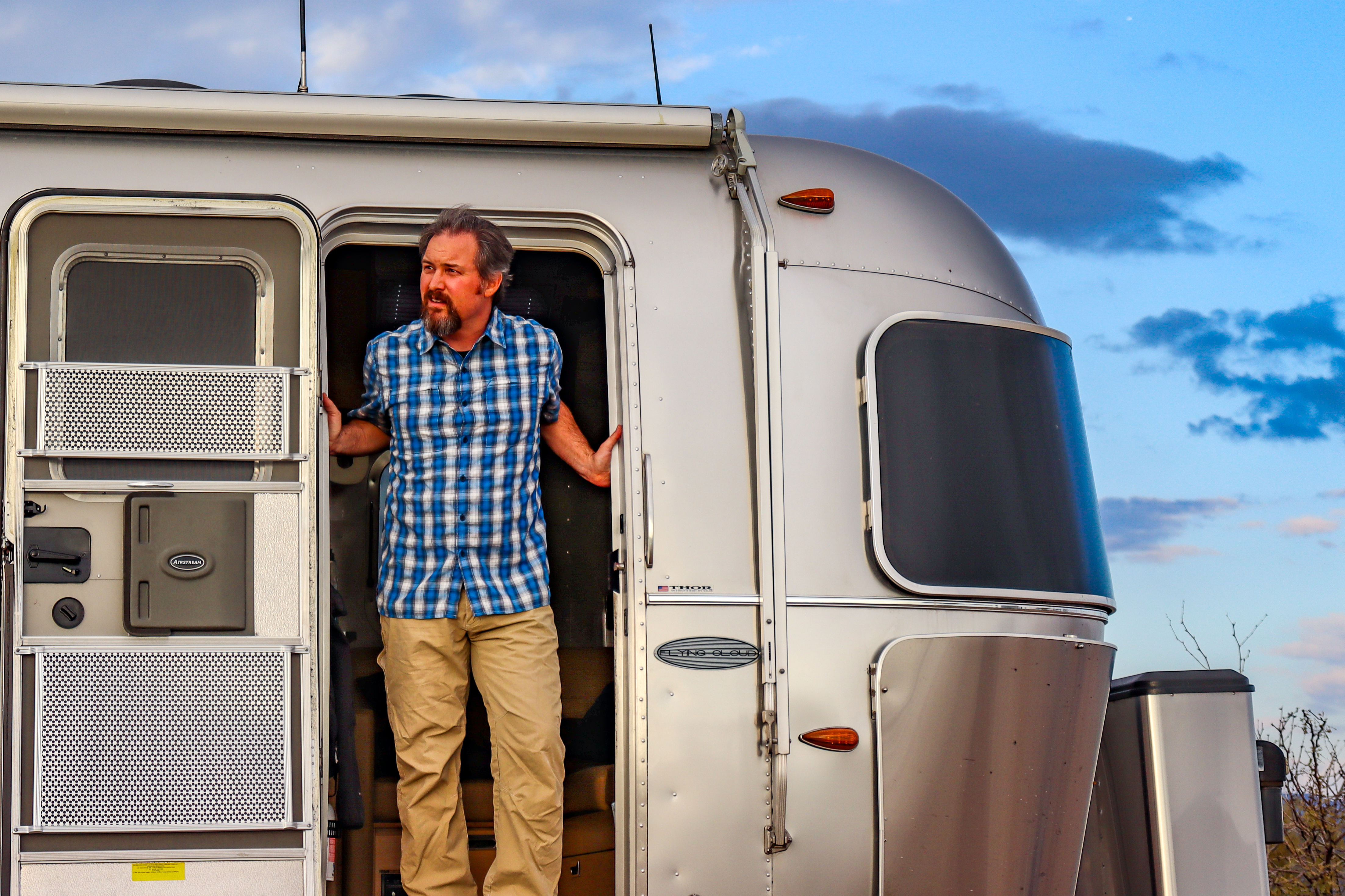 Greg Graham stands at the door of his Airstream.