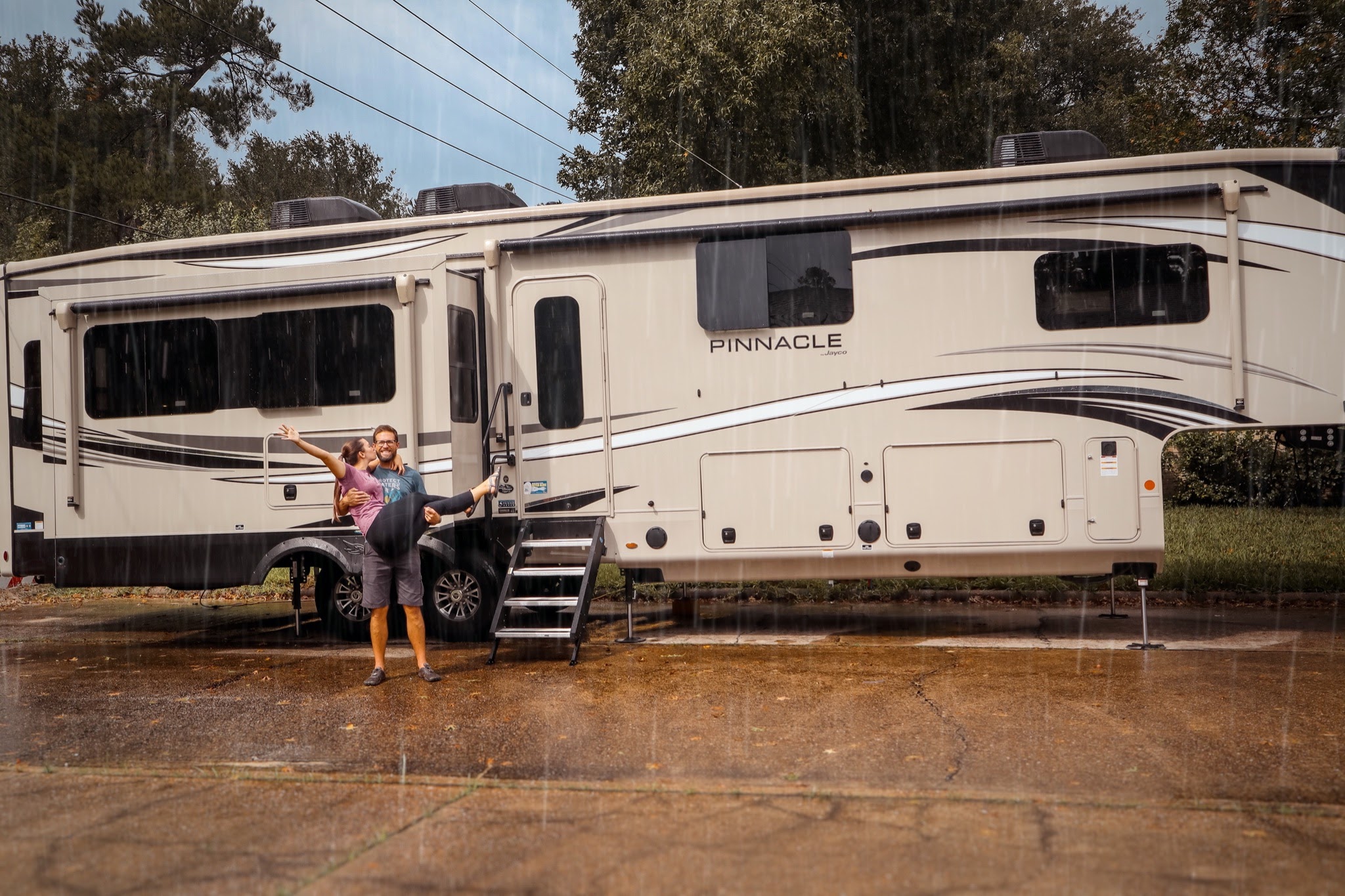 Holly Miner's husband holding her in the rain with their Jayco Pinnacle behind them.