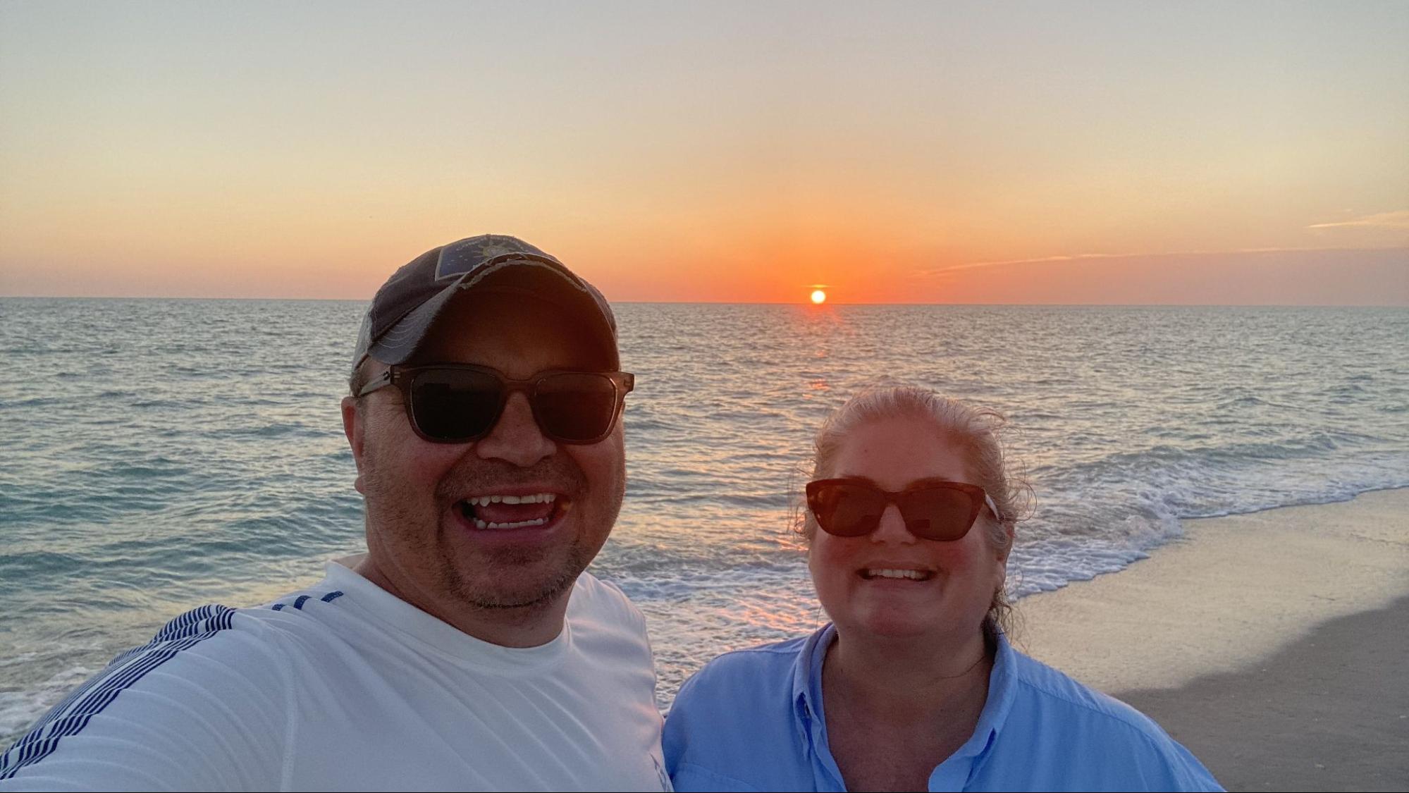 Michael and Tiffany Dunagan take a seflie by the beach at sunset.