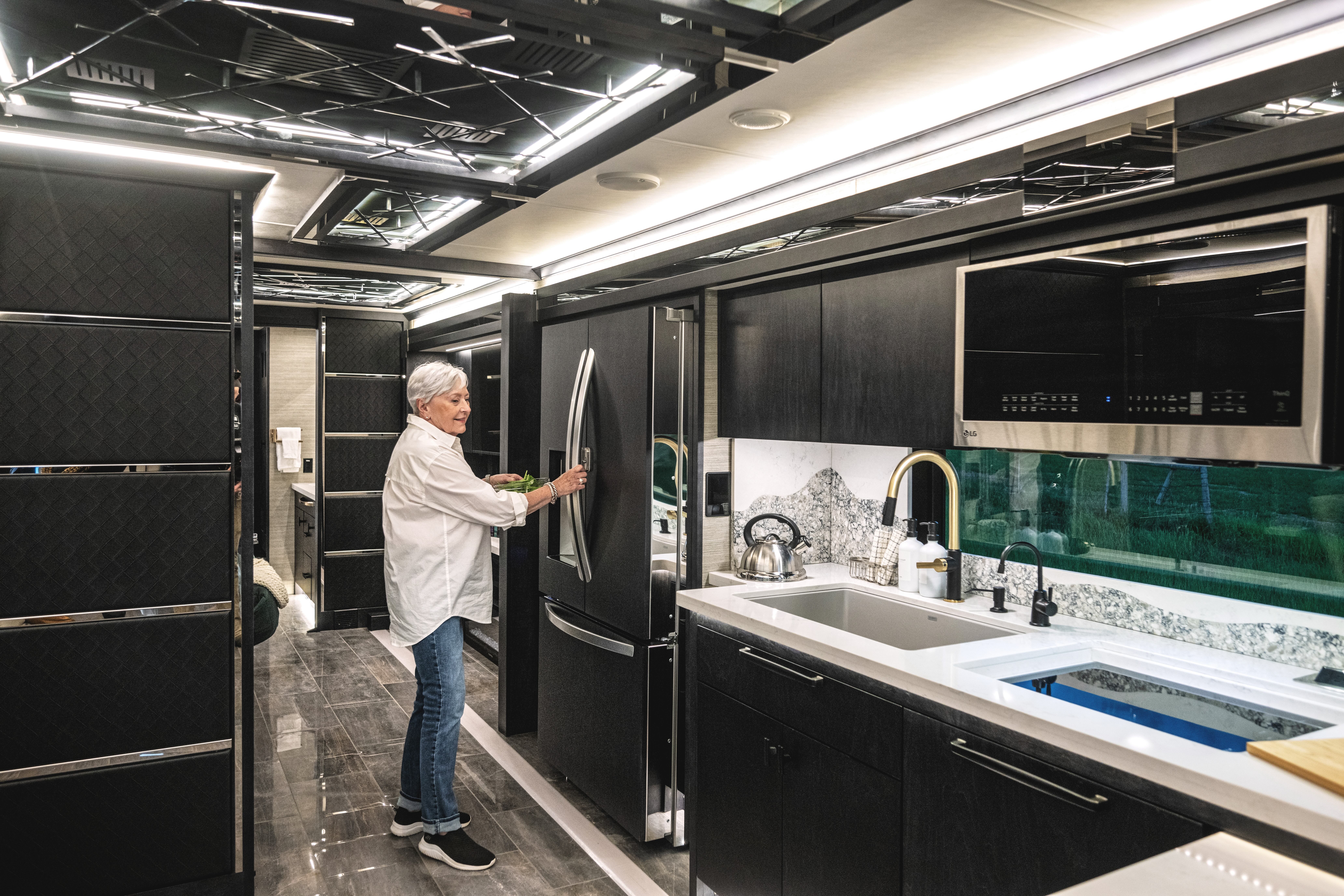 A woman opens a fridge inside the kitchen of a Tiffin Motorhome.