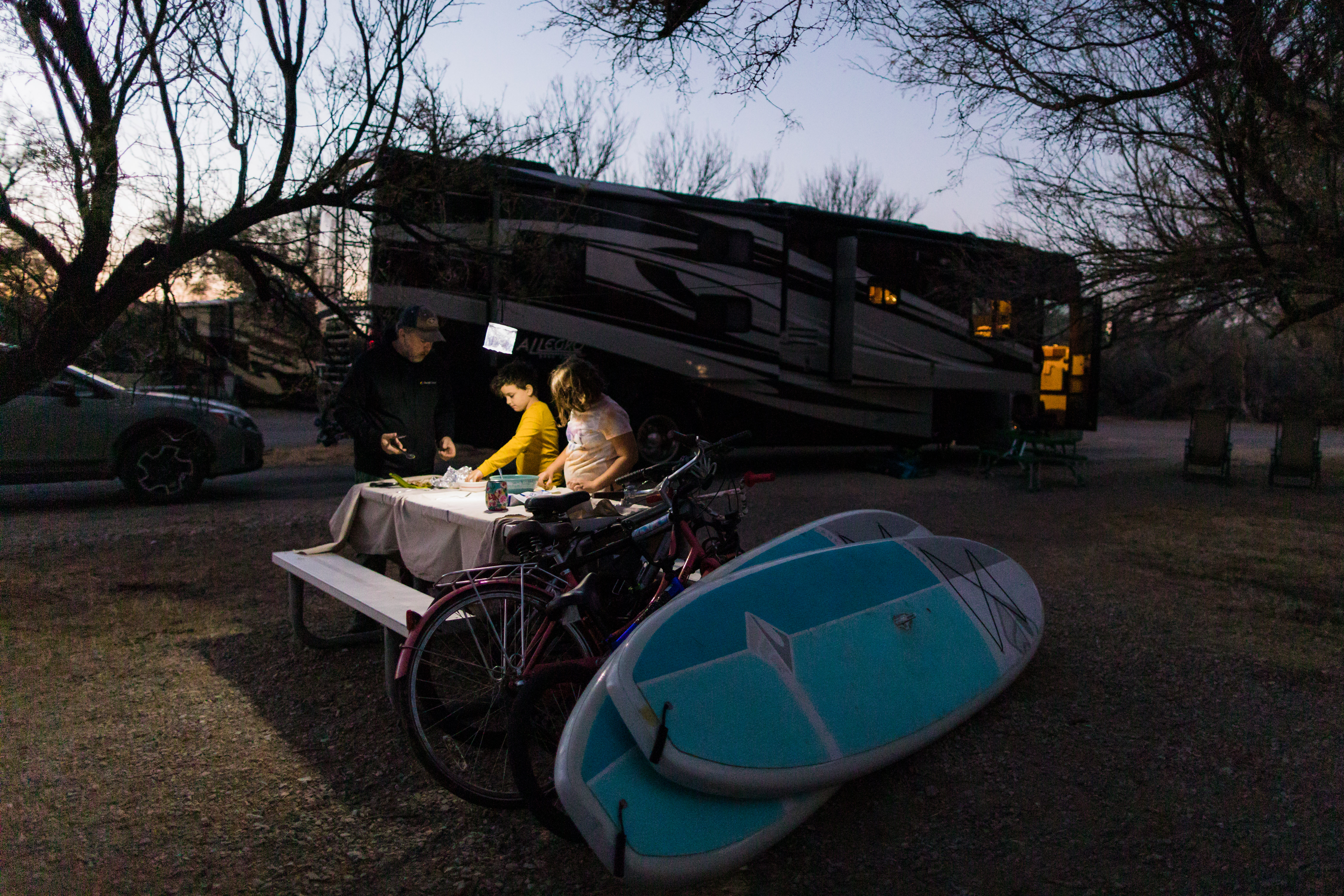 Desiree Walters children and husband set out dinner at dusk at a campsite with their Class A Allegro RV in the background.
