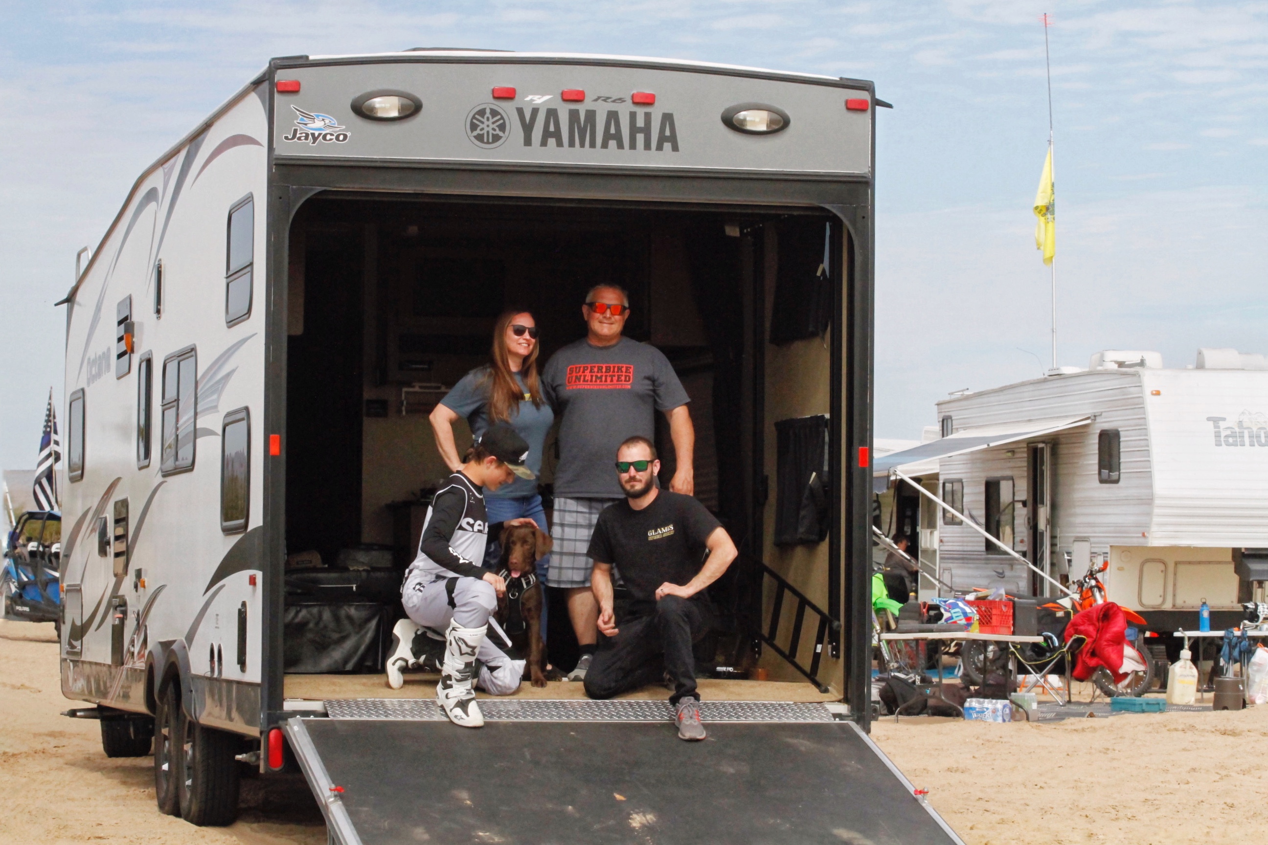 A family of four posed in the back of their Toy Hauler. 