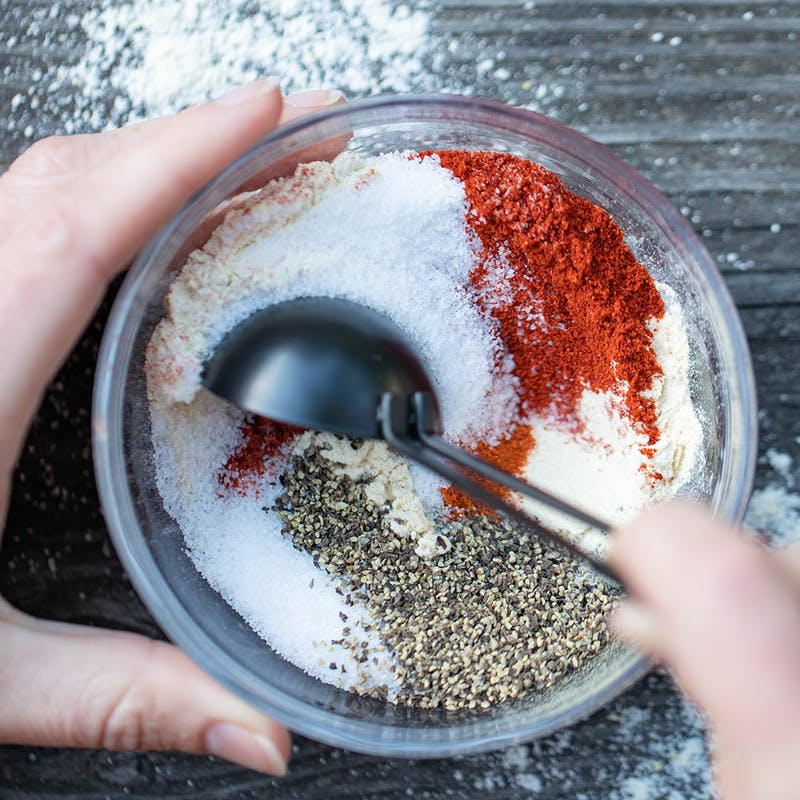 Woman mixes up spices in a bowl using a spoon.