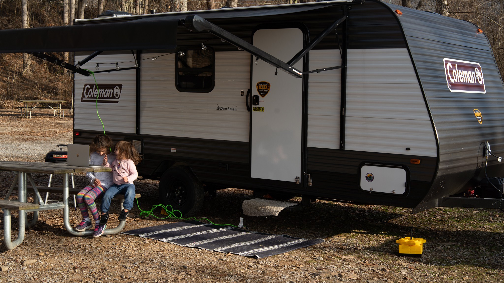 Juan and Johana Oropeza's daughters sit at a picnic table by their Coleman travel.