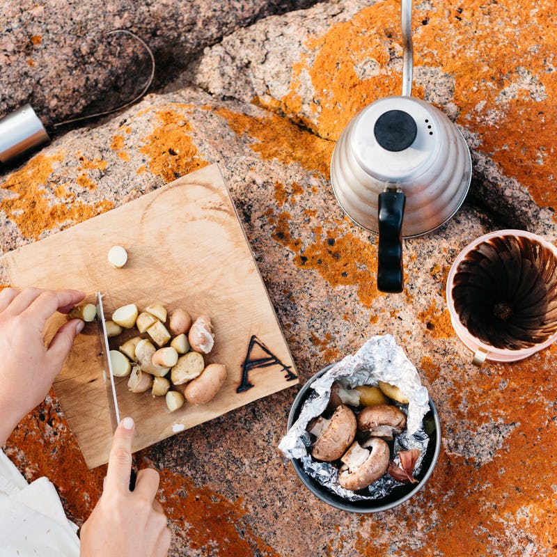 Cutting potatoes on a cutting board, with a bowl of mushrooms and fresh brewed coffee.