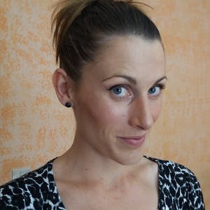 A close up picture of Chiara Martinelli, wearing a black and white leopard print shirt, her hair pulled back, with a subtle smile.