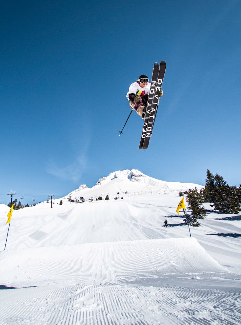 Ryan in mid-air on his skis after launching off a snow jump.