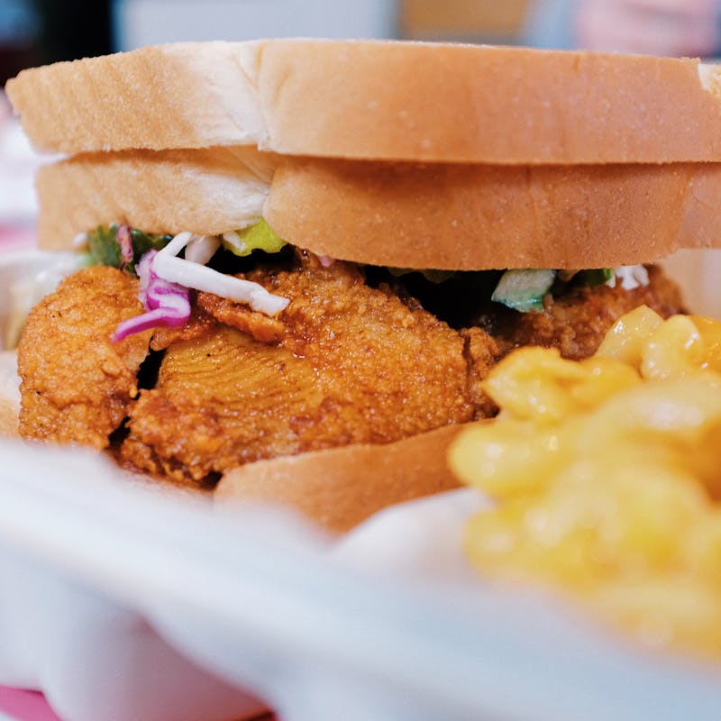 Close up of fried chicken sandwich with slaw and side of mac and cheese.